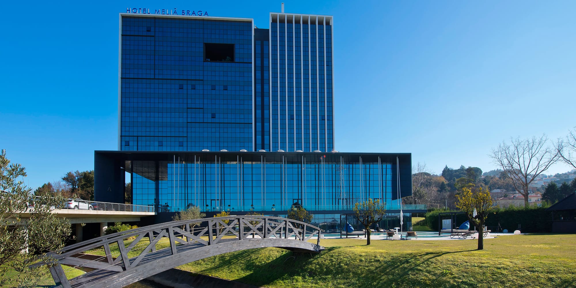 a bridge over a grass field with a building in the background