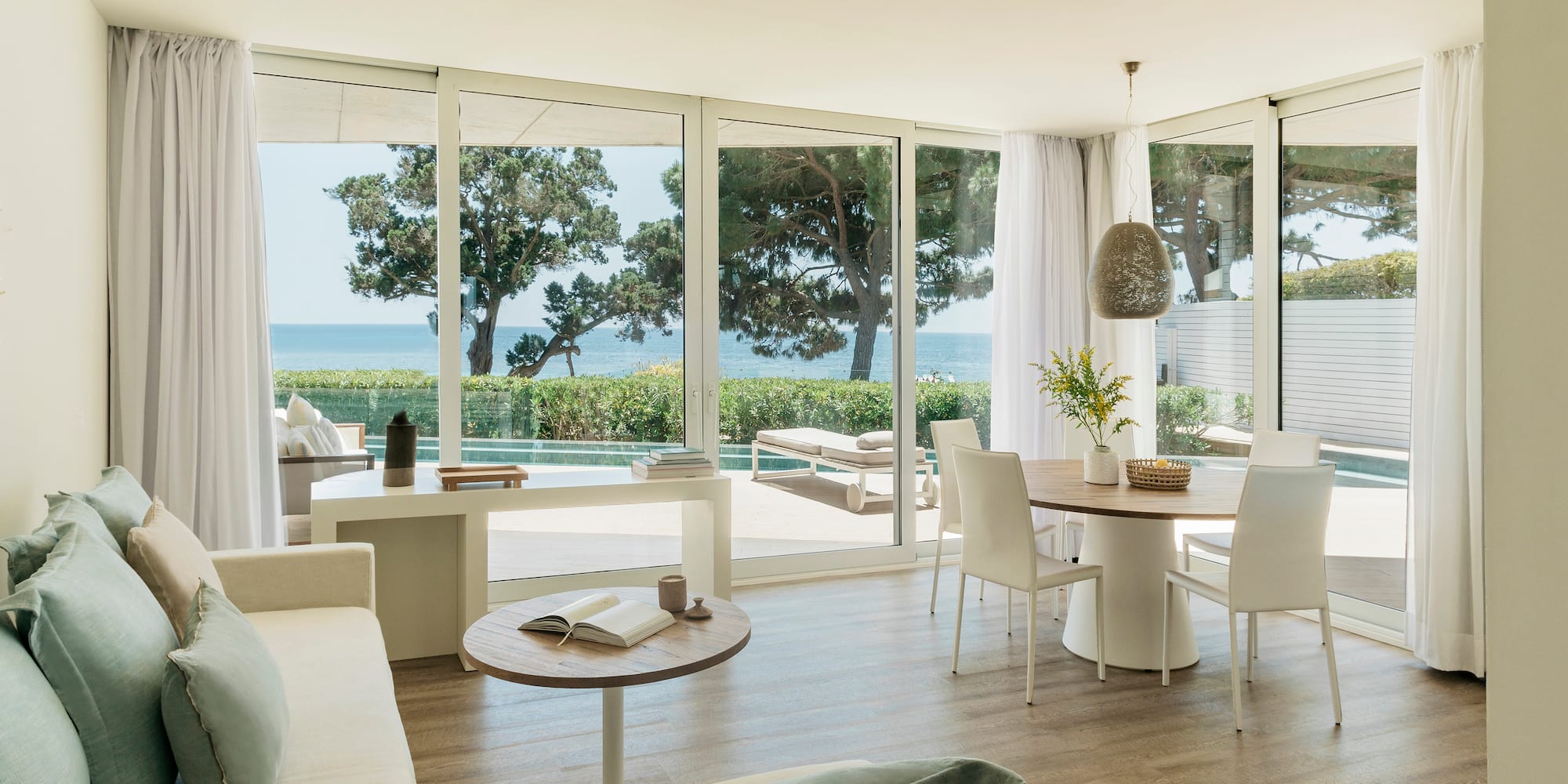 a living room with a table and chairs and a table with chairs and a table with a view of the ocean