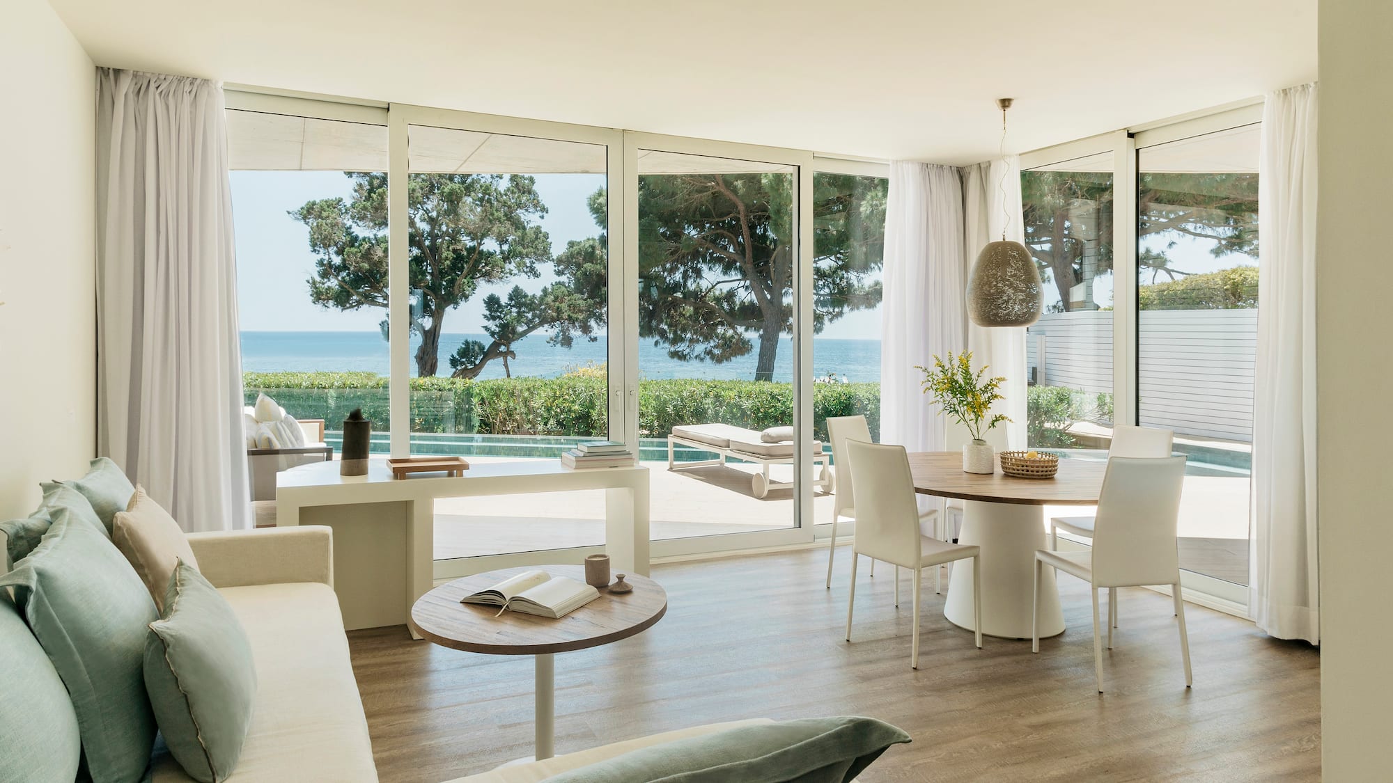 a living room with a table and chairs and a table with chairs and a table with a view of the ocean