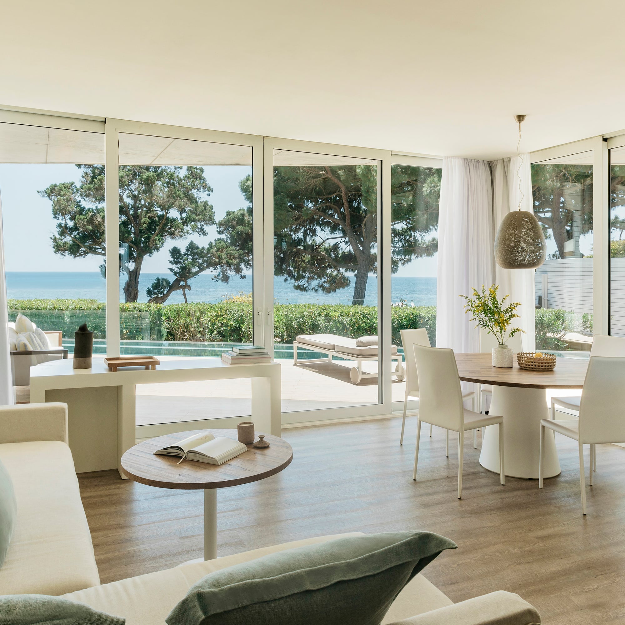 a living room with a table and chairs and a table with chairs and a table with a view of the ocean