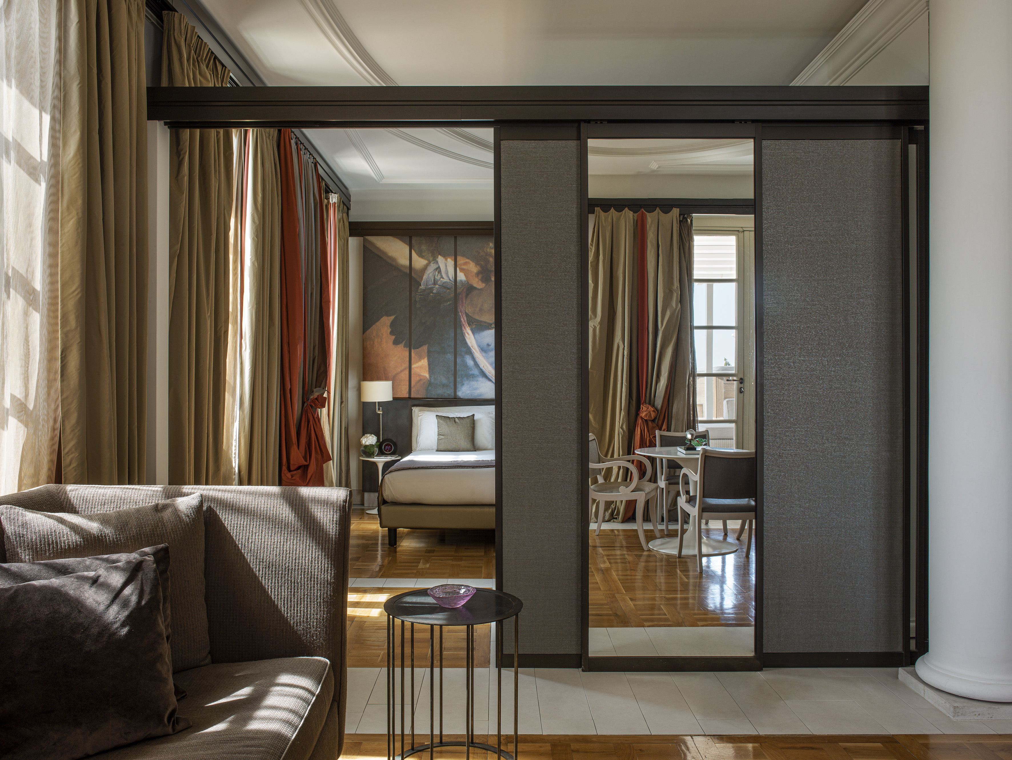 Luxury hotel suite with living area, bedroom, and sliding partition.