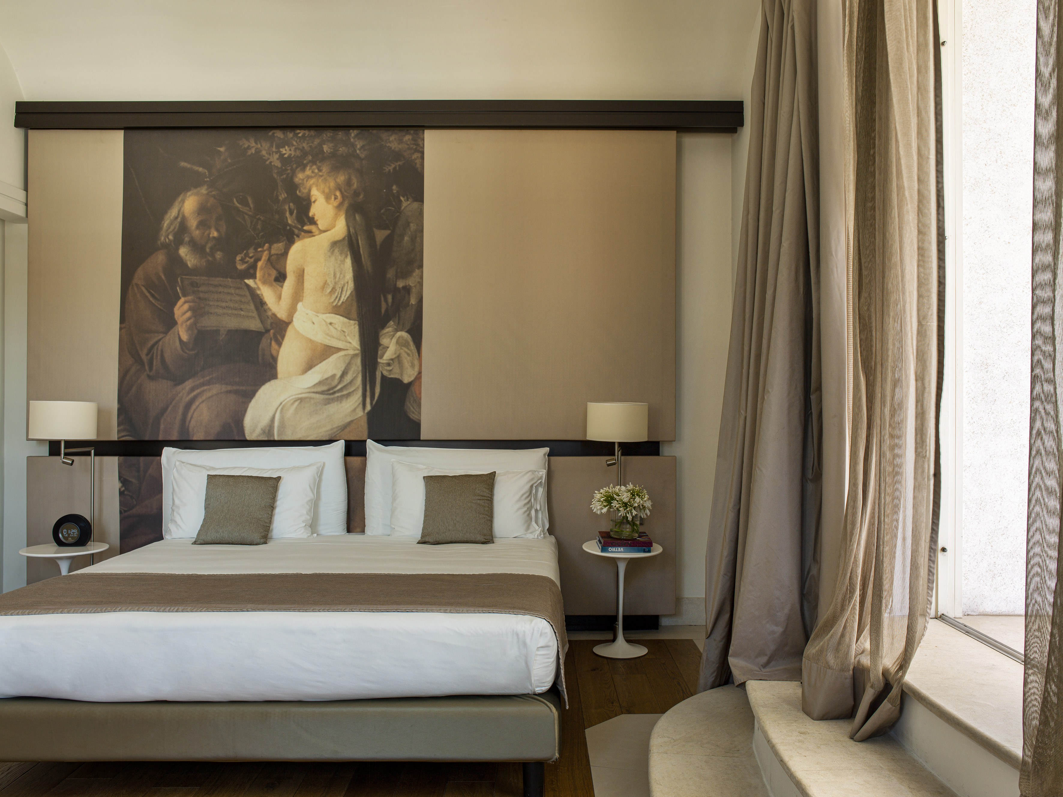 Elegant bedroom with large bed, classical art mural, and neutral decor.