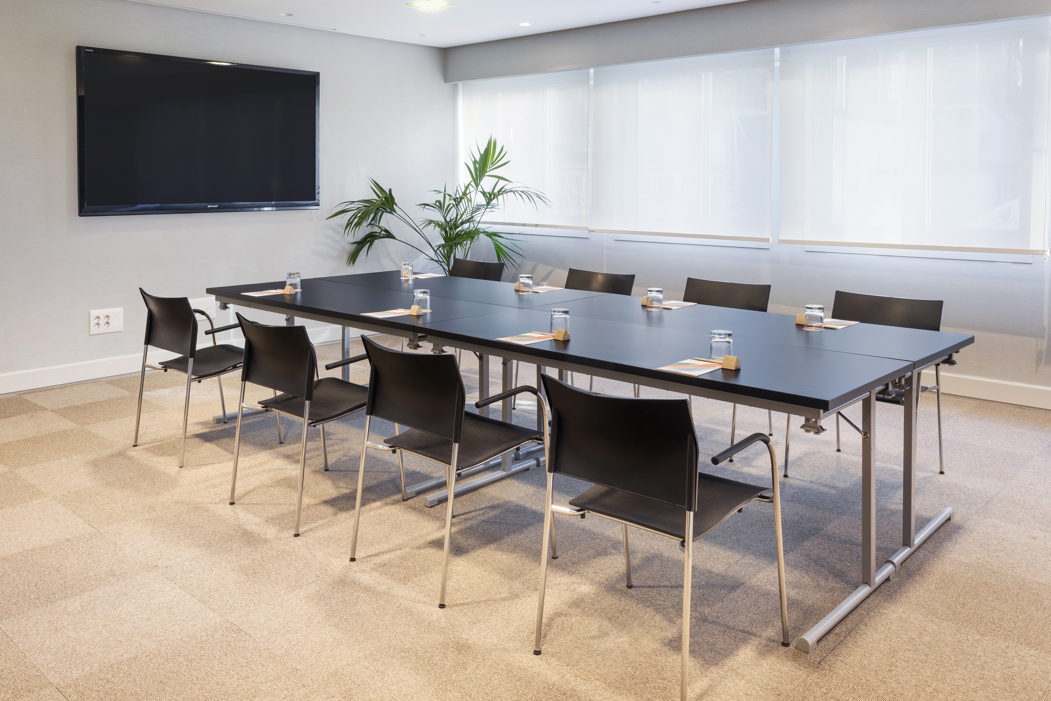 Sleek corporate meeting room with long black table, chairs, and large TV.