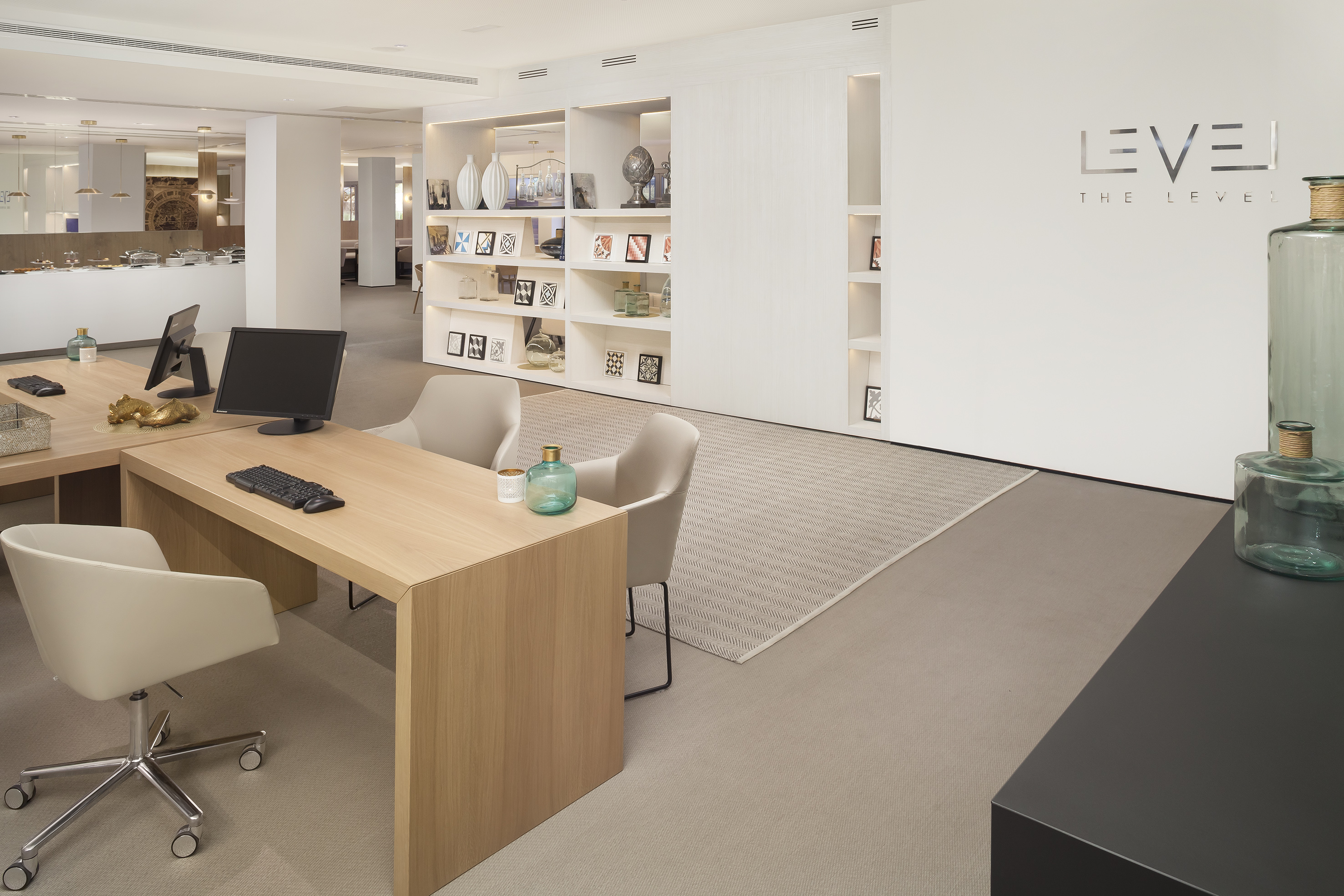 Modern hotel reception desk, computers, white shelving, and THE LEVEL logo.