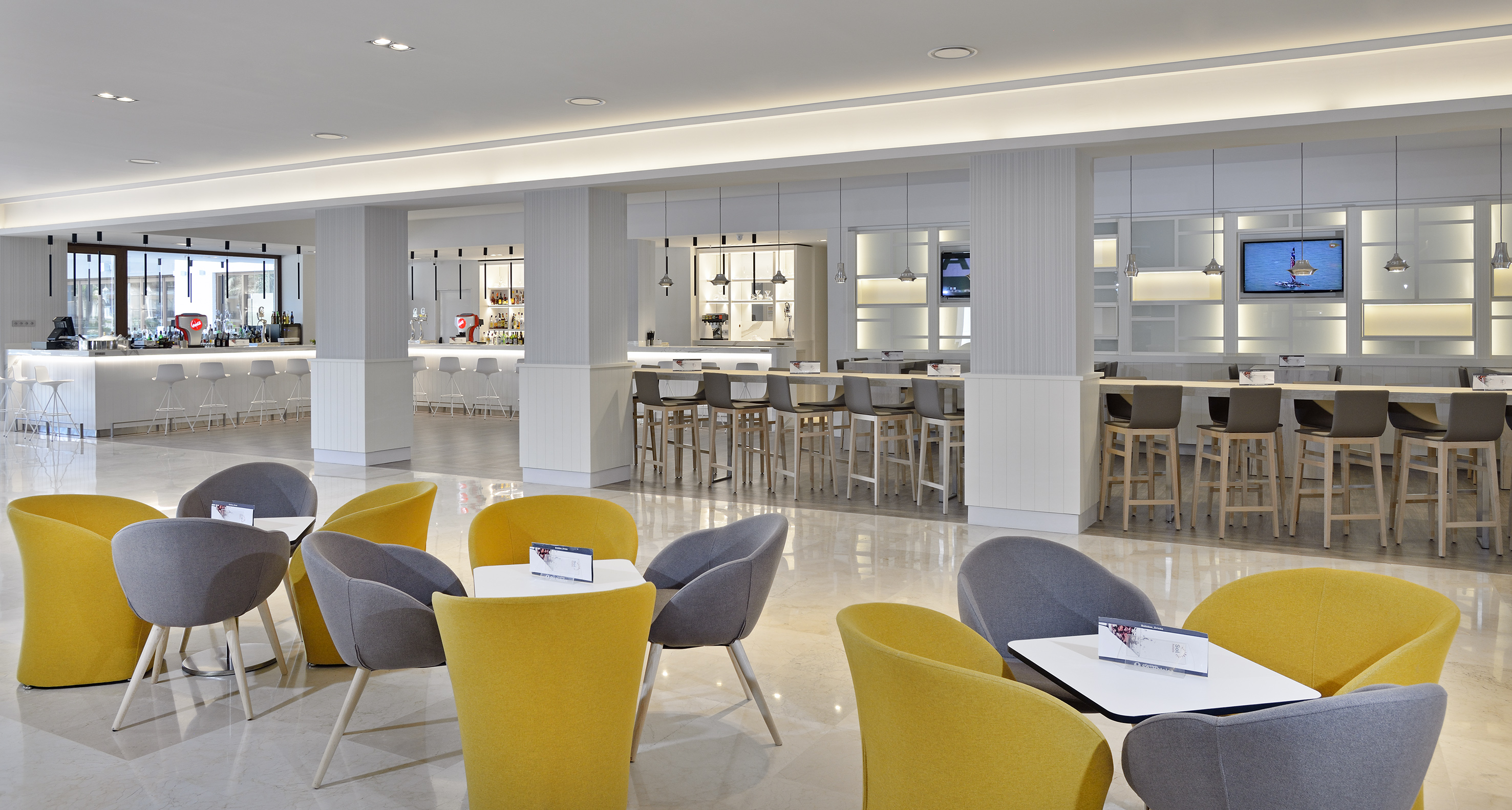 Contemporary hotel lobby lounge with yellow and grey chairs and white bar.