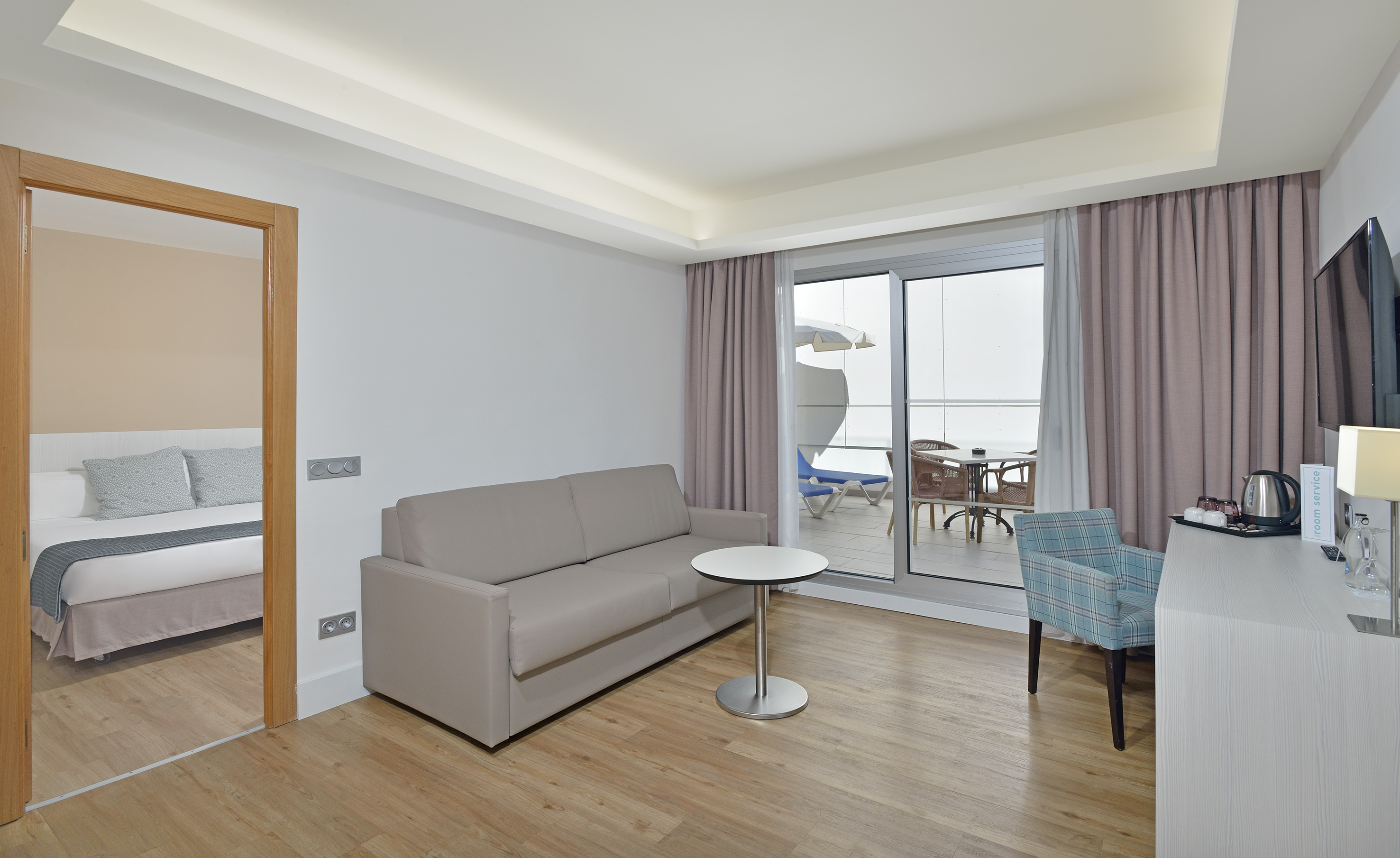 Modern hotel suite with living area, separate bedroom, and balcony.