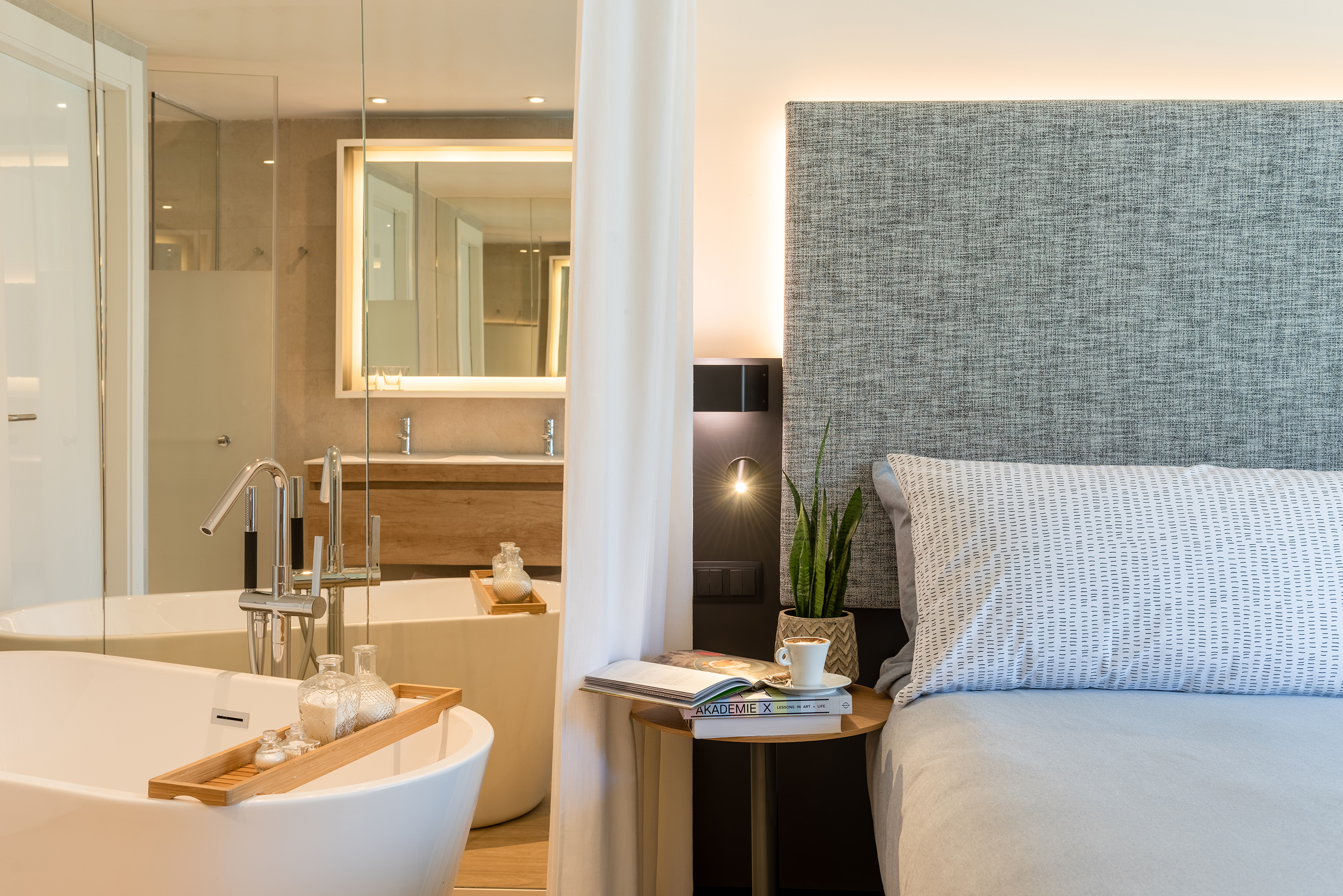 Luxury open-concept suite with modern bedroom and freestanding bathtub.