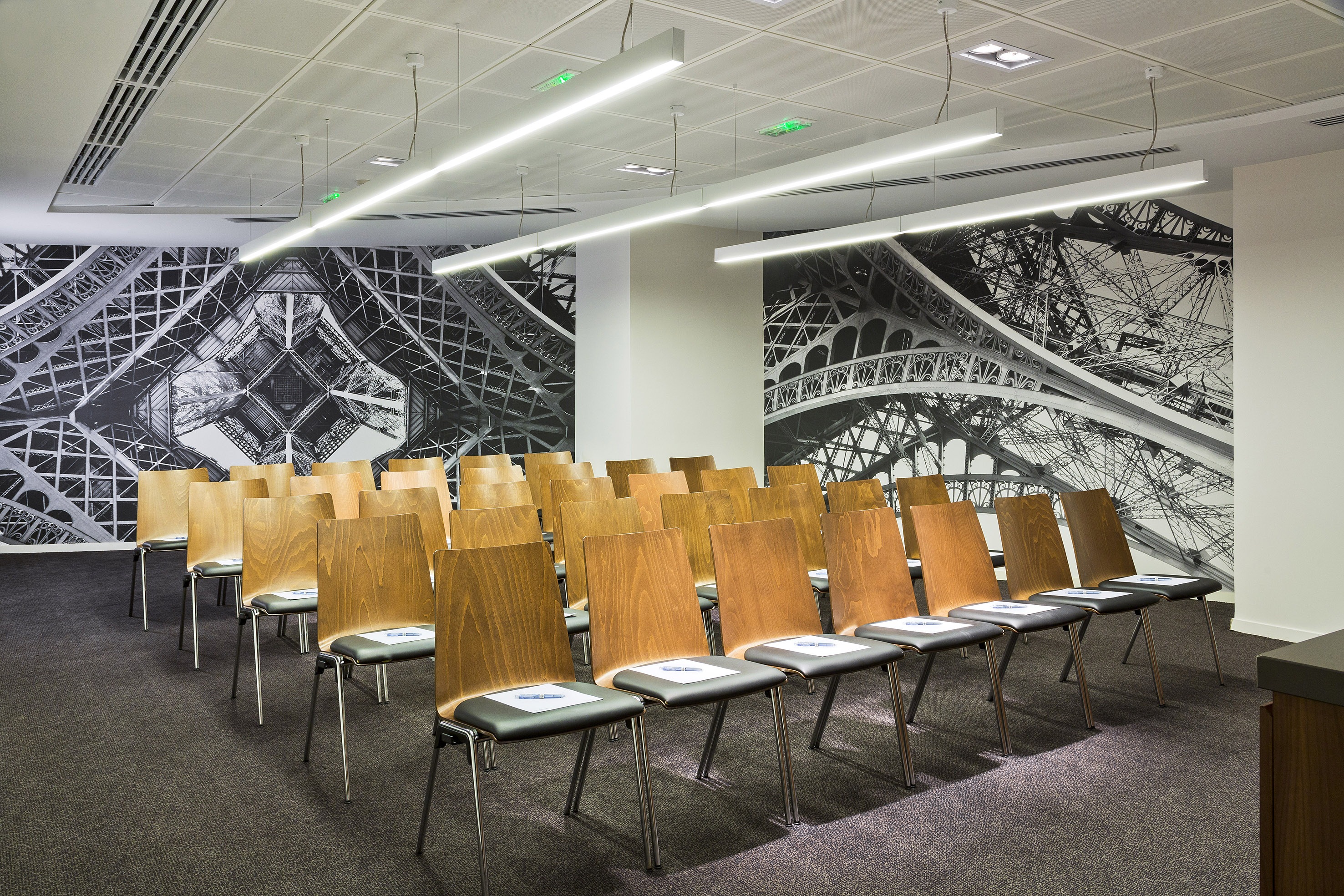 Modern conference room with Eiffel Tower wall mural and rows of wooden chairs.