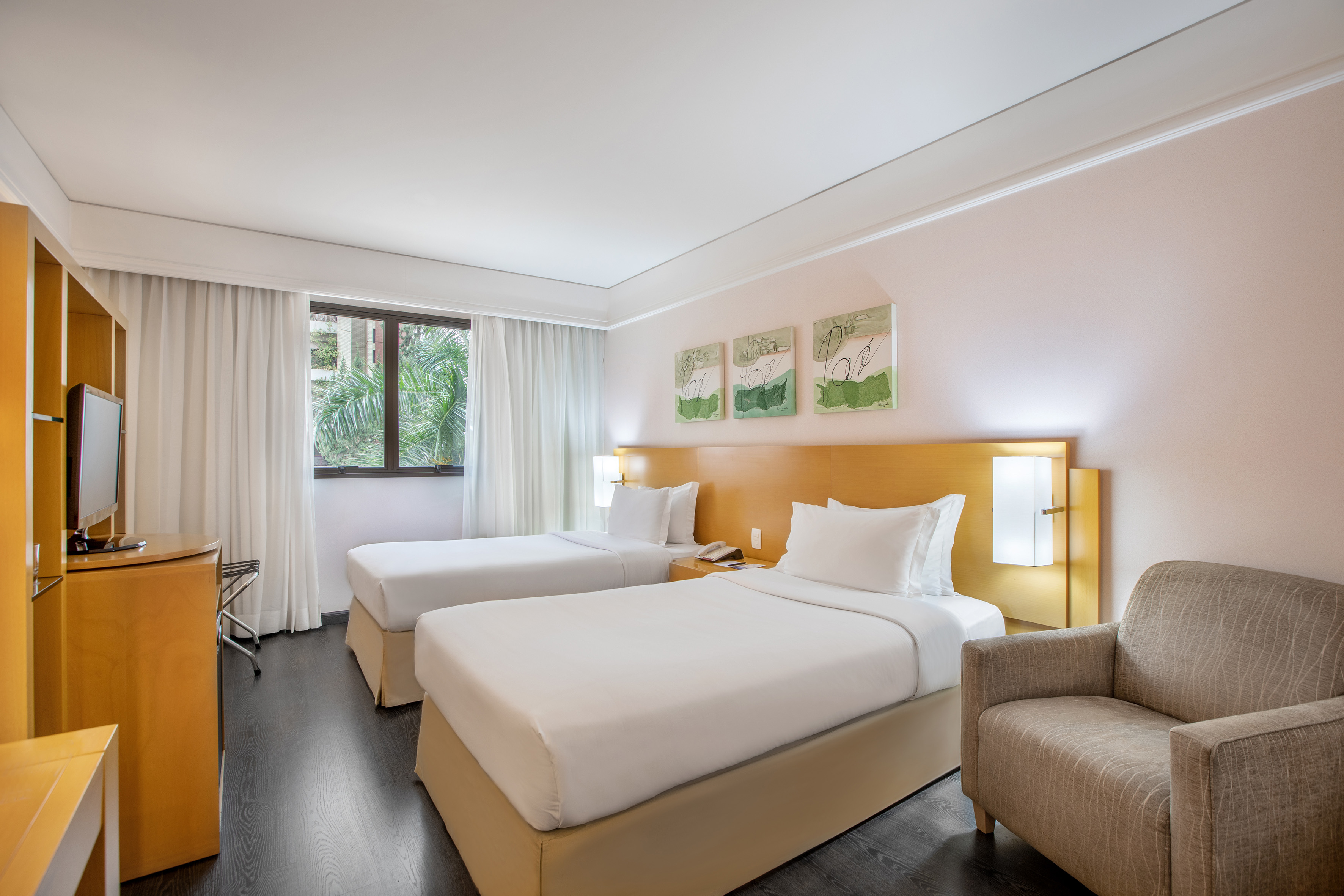 Modern hotel room with two twin beds, dark floor, and window view.