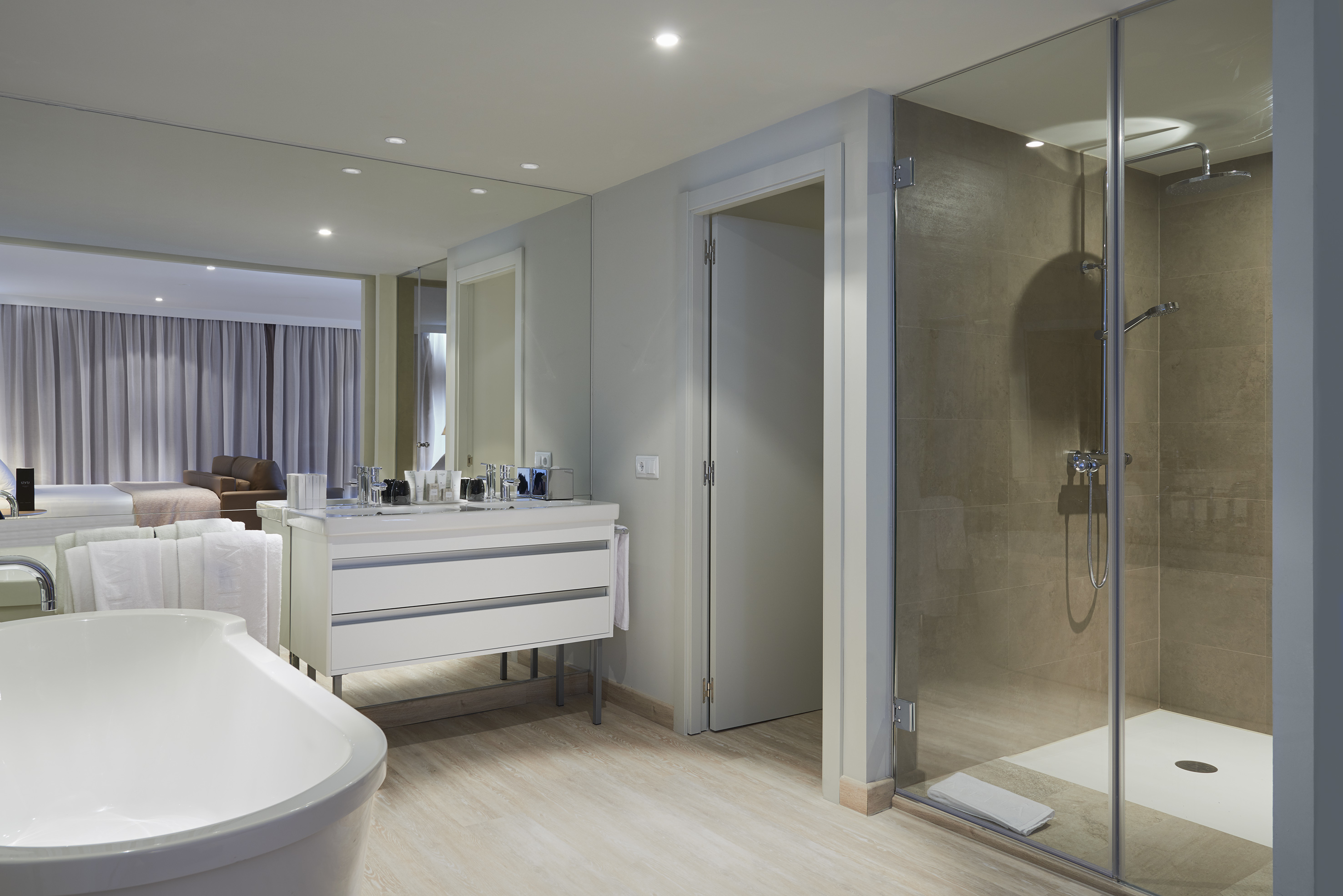 Modern hotel bathroom featuring bathtub, dual vanity, and glass shower.