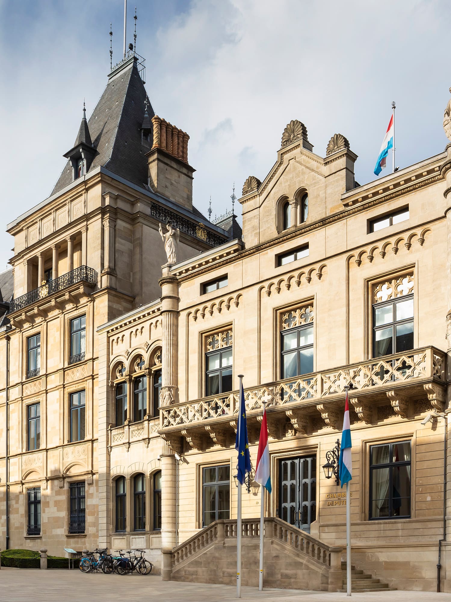 a large stone building with flags with Grand Ducal Palace, Luxembourg in the background