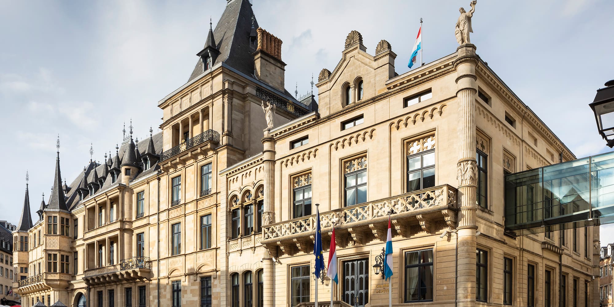 a large stone building with flags with Grand Ducal Palace, Luxembourg in the background