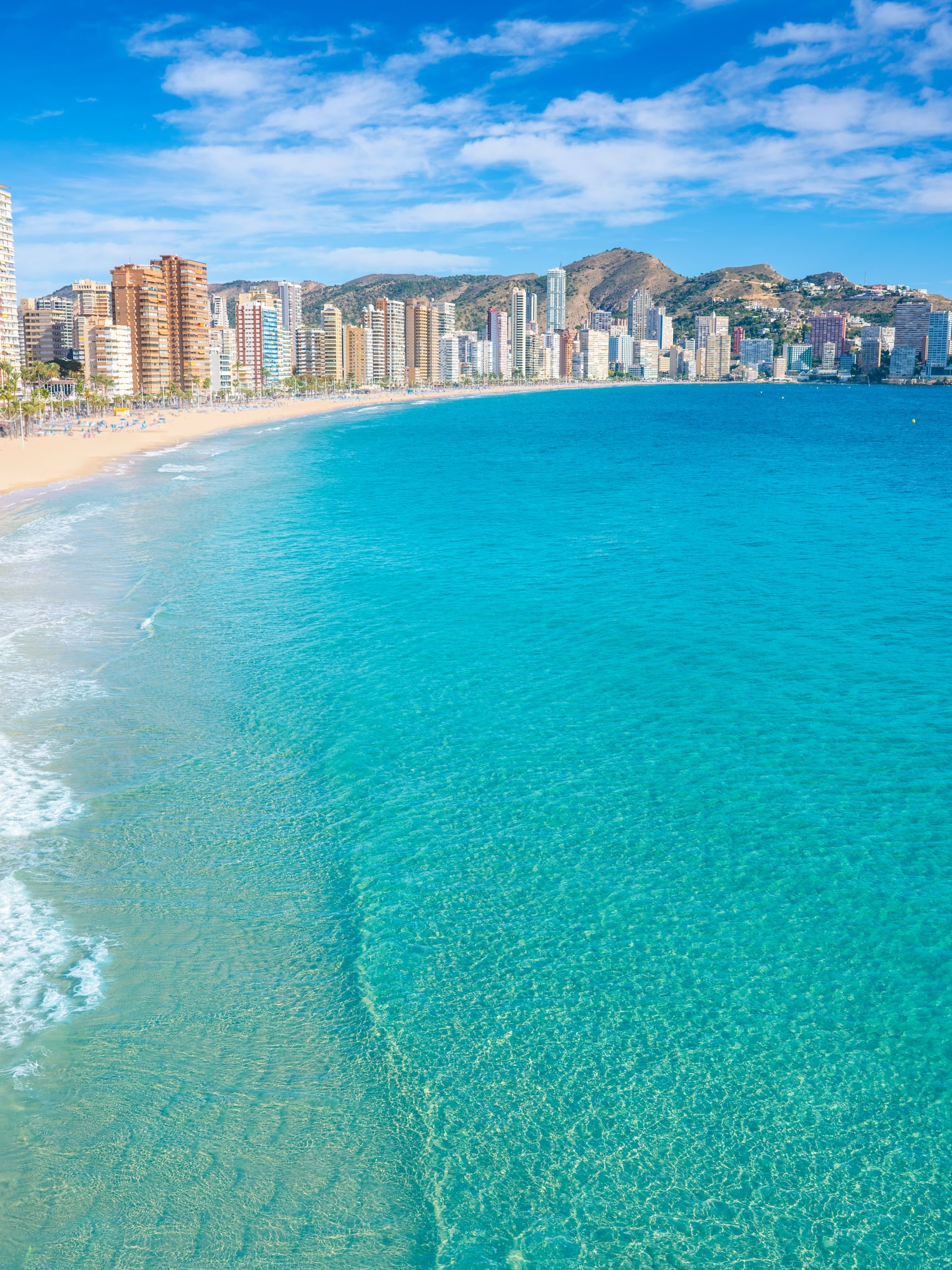 a beach with buildings and blue water