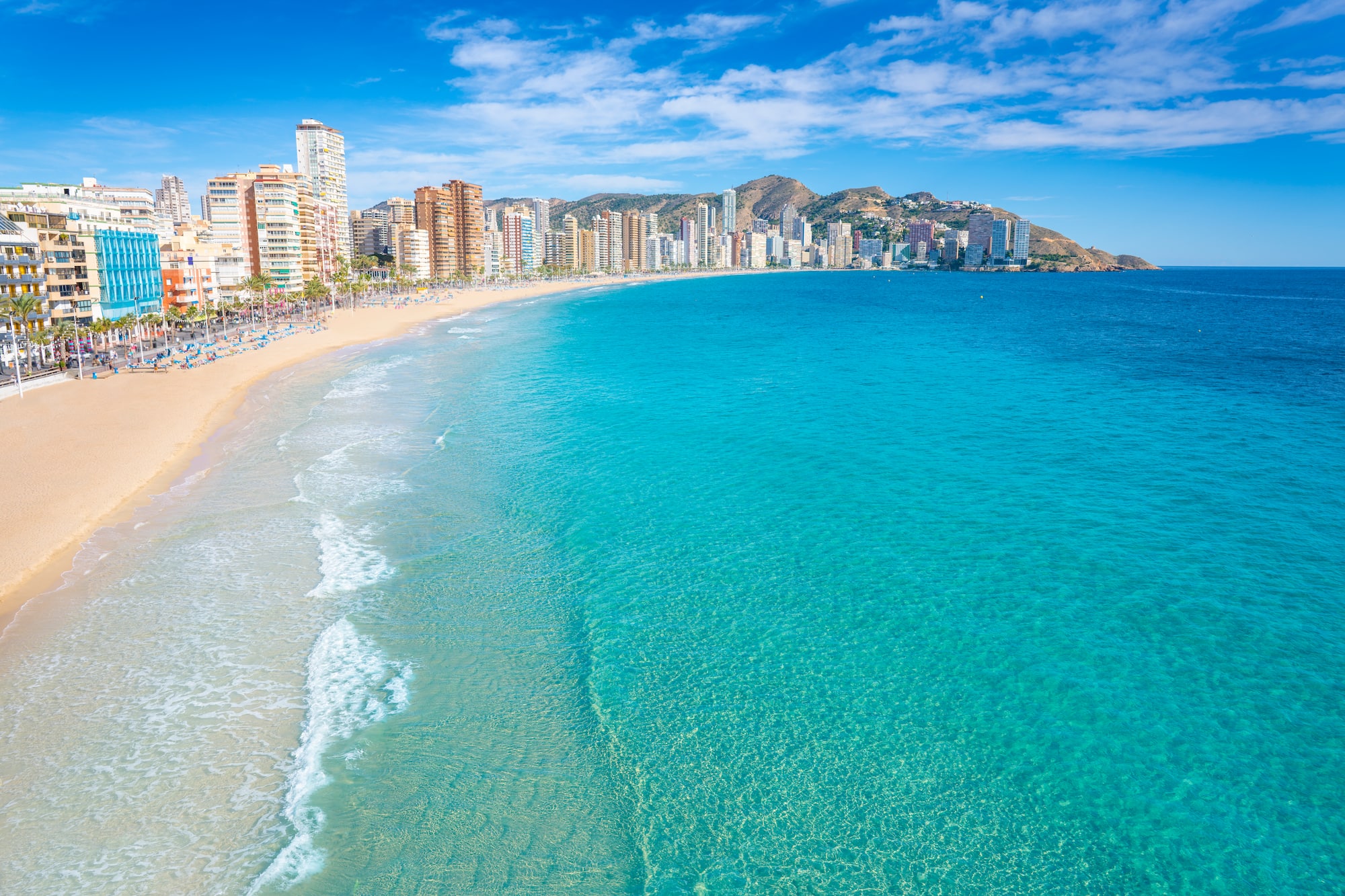 a beach with buildings and blue water