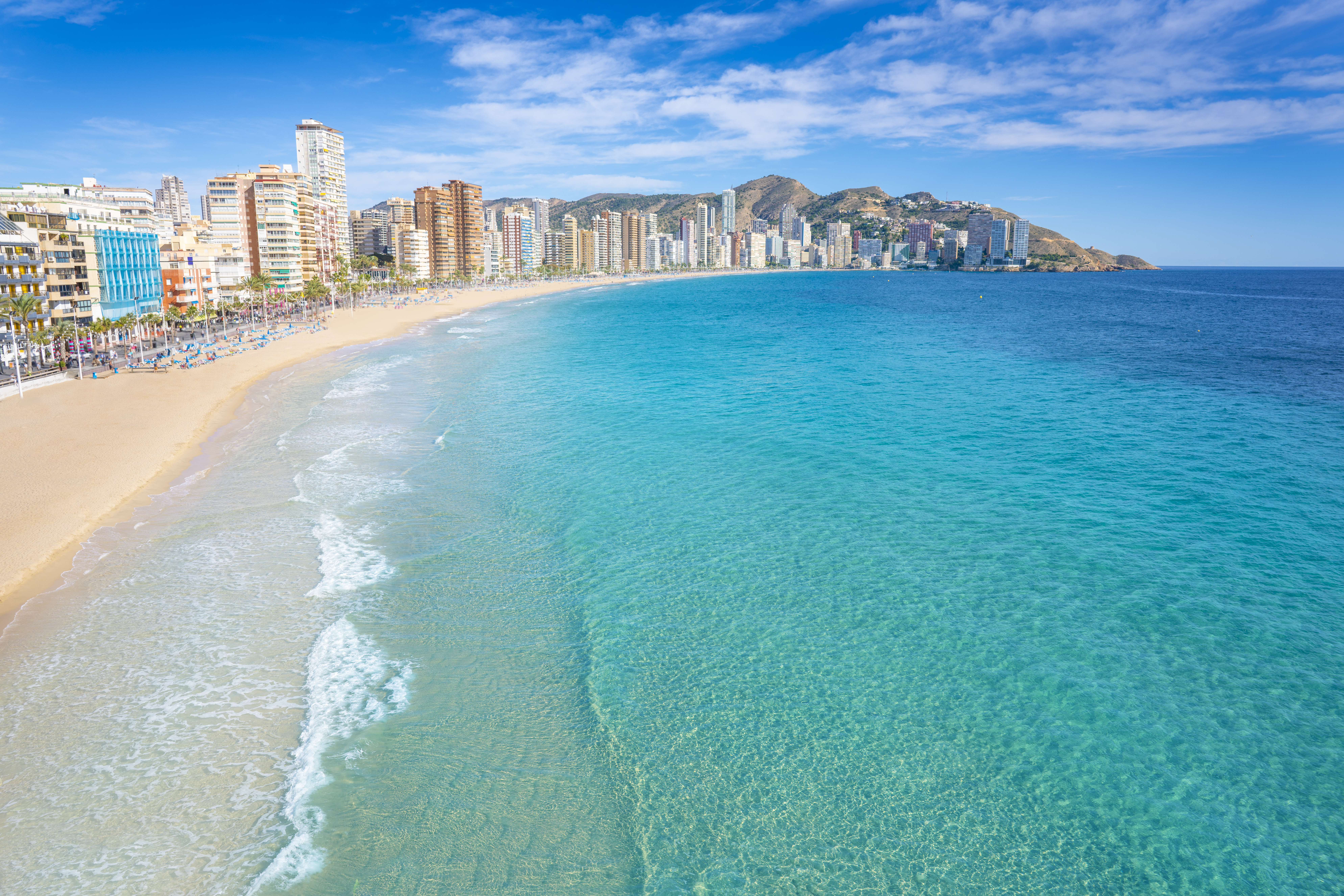 a beach with buildings and blue water