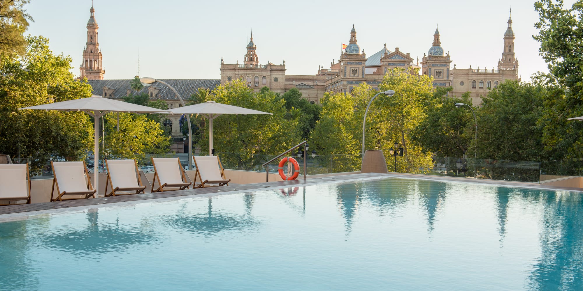 a pool with chairs and umbrellas in front of a building
