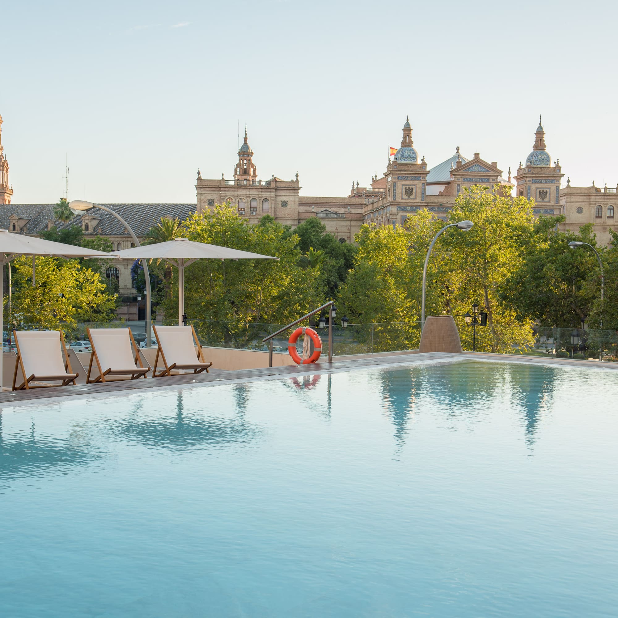 a pool with chairs and umbrellas in front of a building