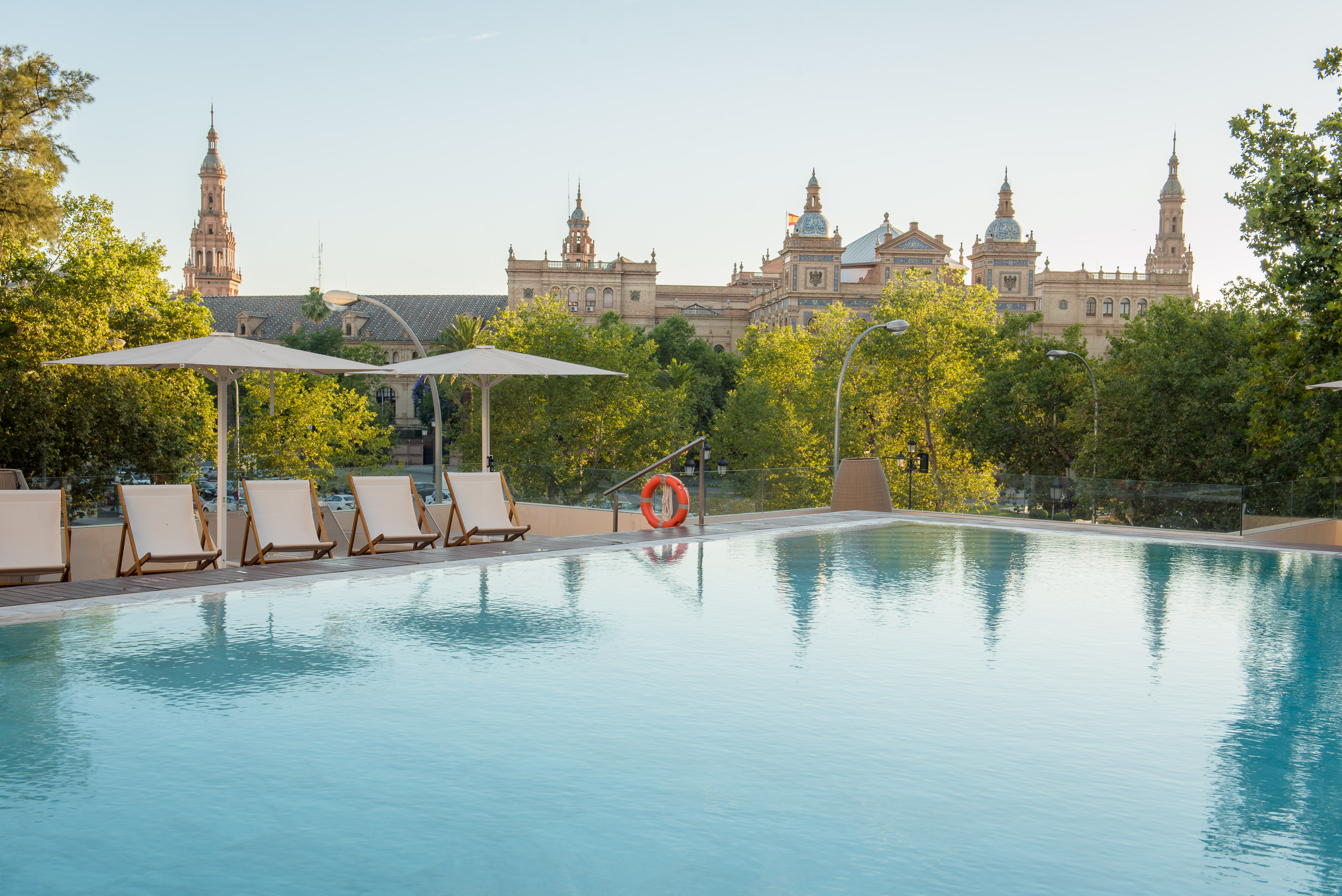 a pool with chairs and umbrellas in front of a building