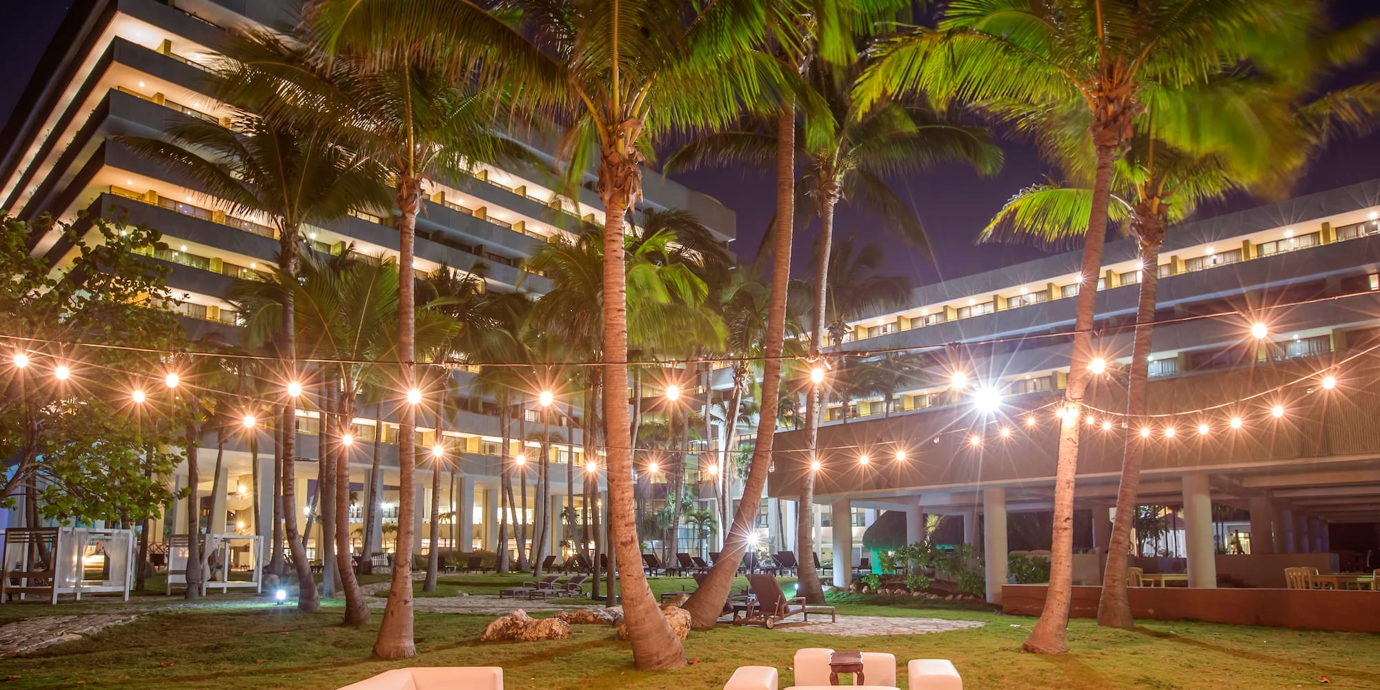 a group of white chairs and palm trees in front of a building