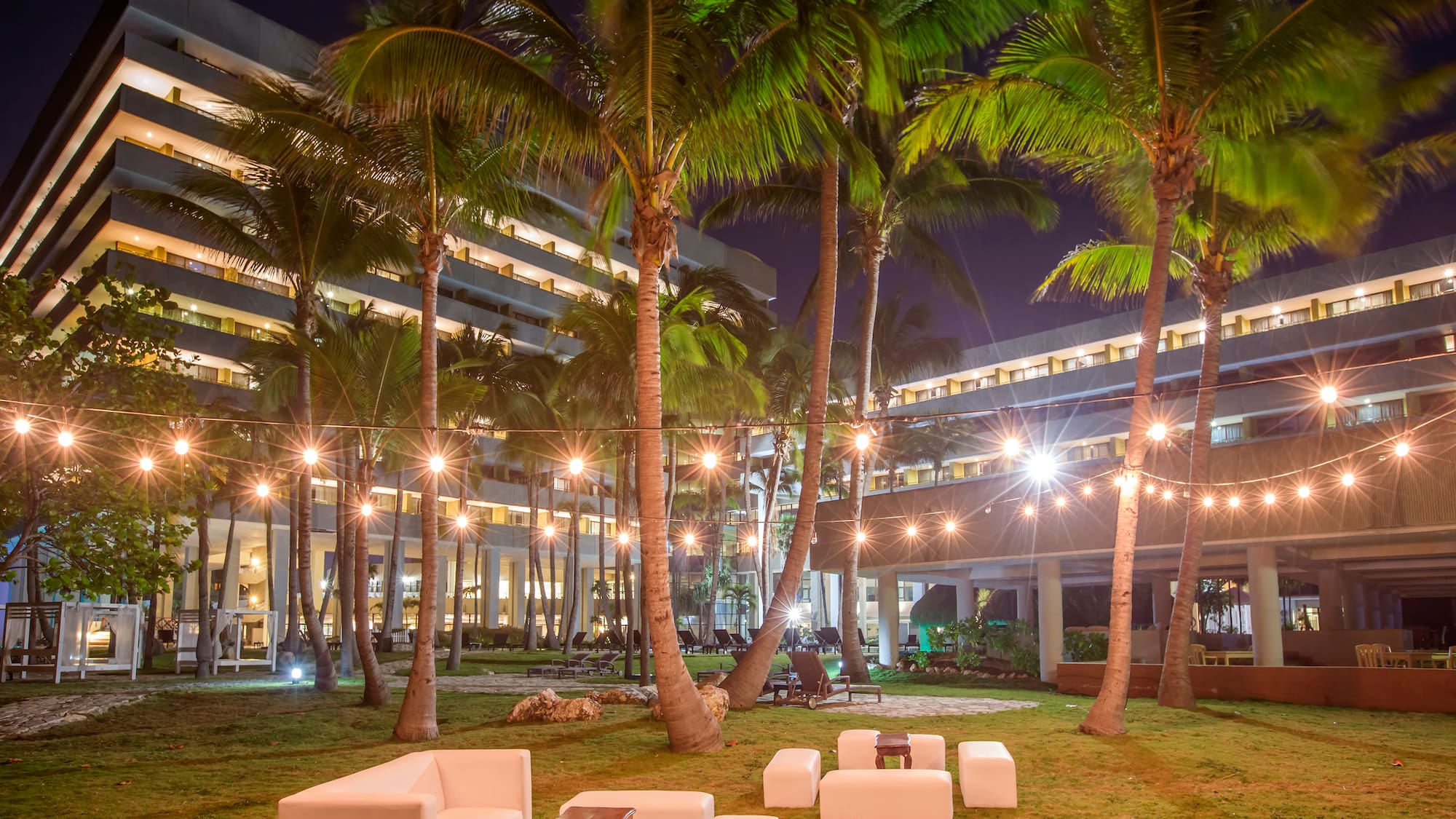 a group of white chairs and palm trees in front of a building