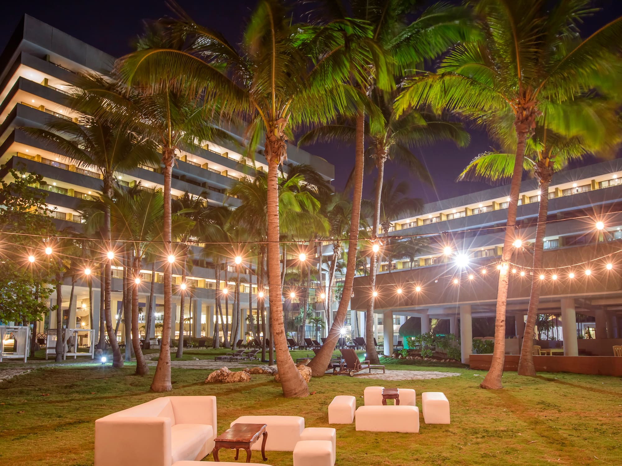 a group of white chairs and palm trees in front of a building