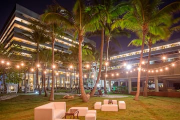 a group of white chairs and palm trees in front of a building