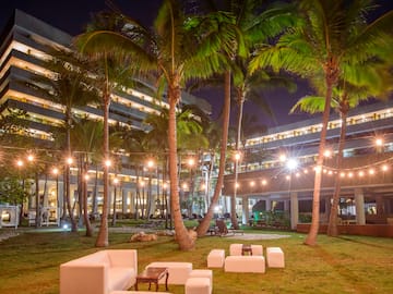 a group of white chairs and palm trees in front of a building