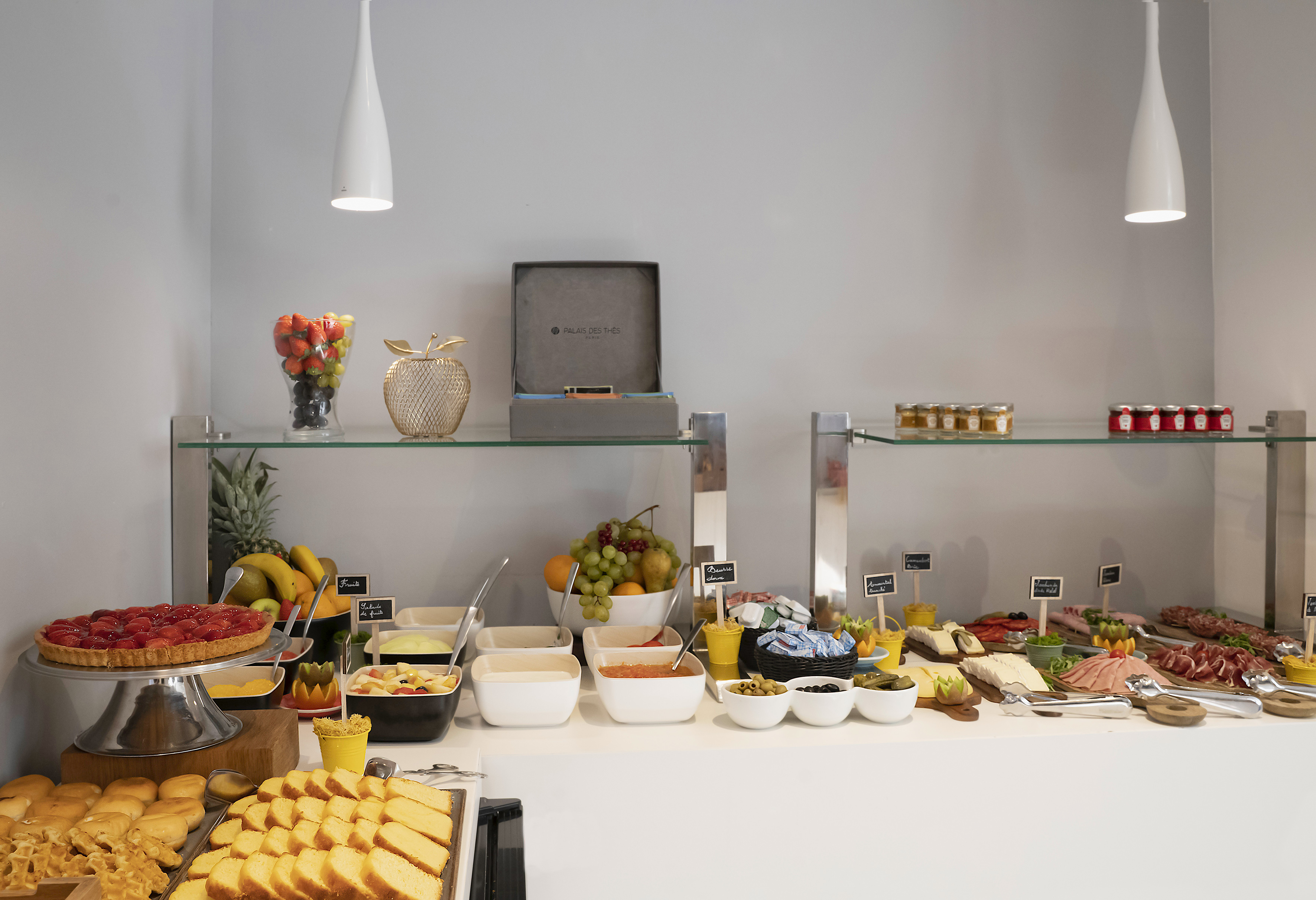 Hotel breakfast buffet with fresh fruit, pastries, cheeses, and cold cuts.