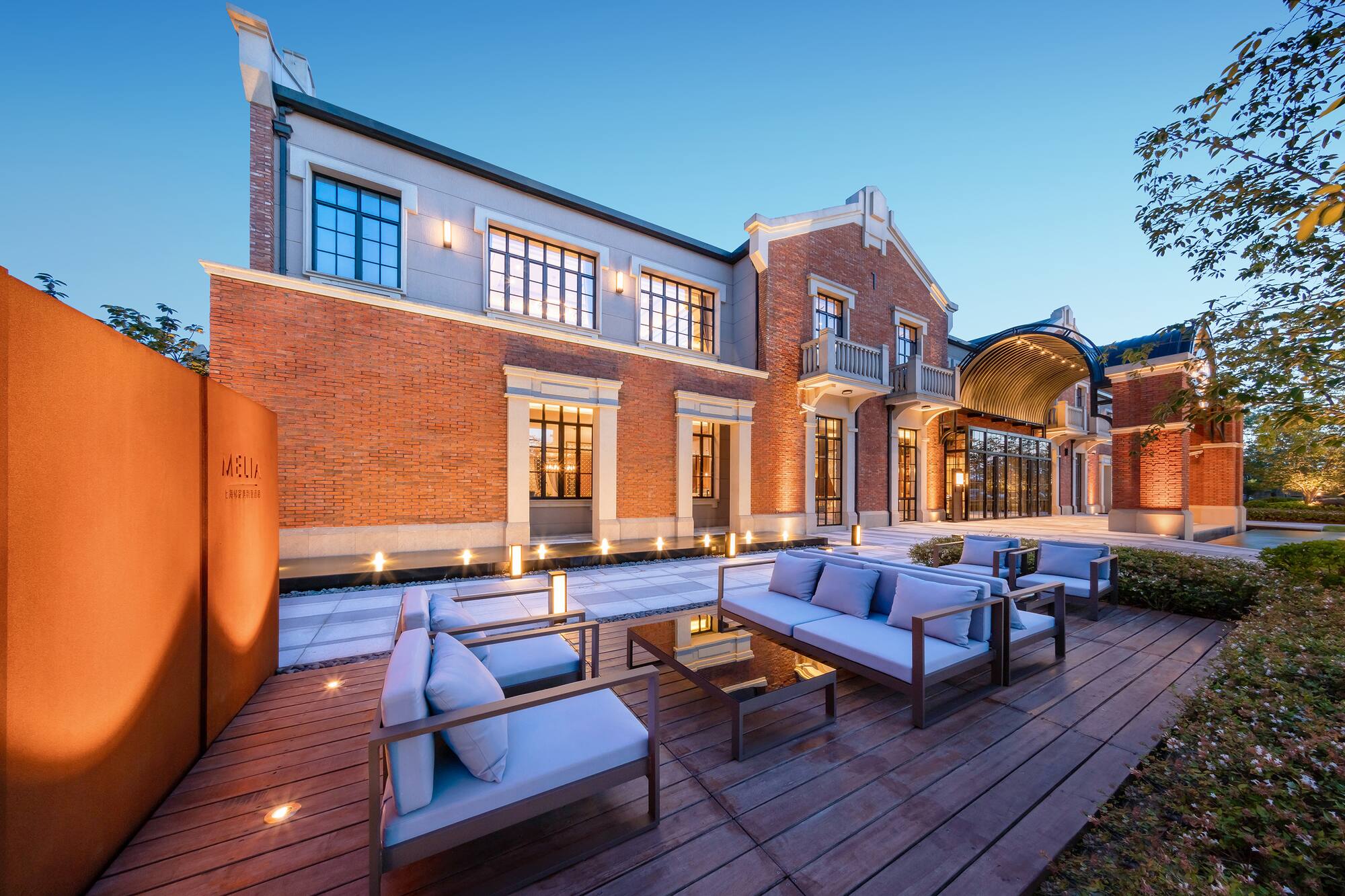 Melia hotel exterior, modern brick building with illuminated outdoor patio lounge.