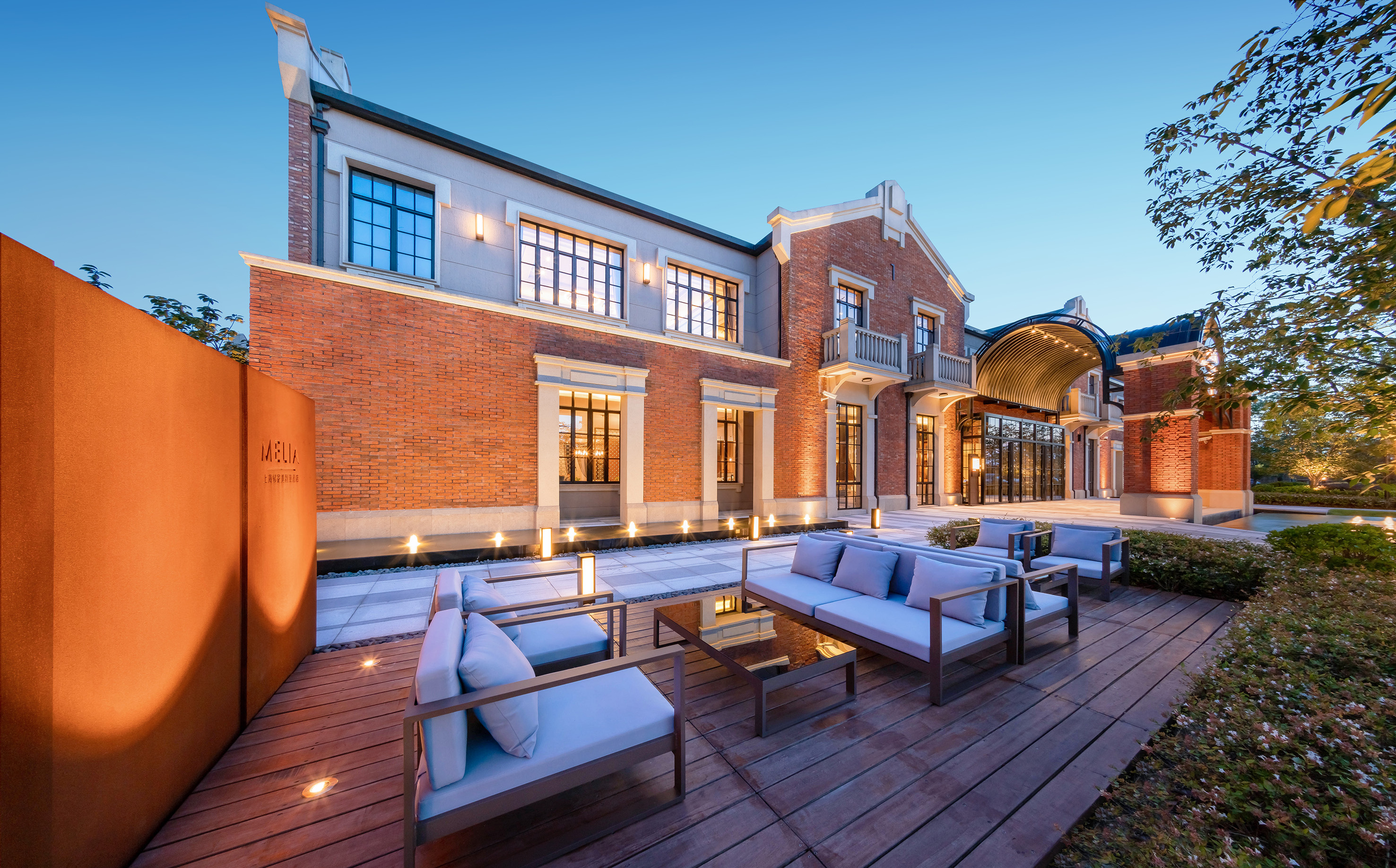Melia hotel exterior, modern brick building with illuminated outdoor patio lounge.