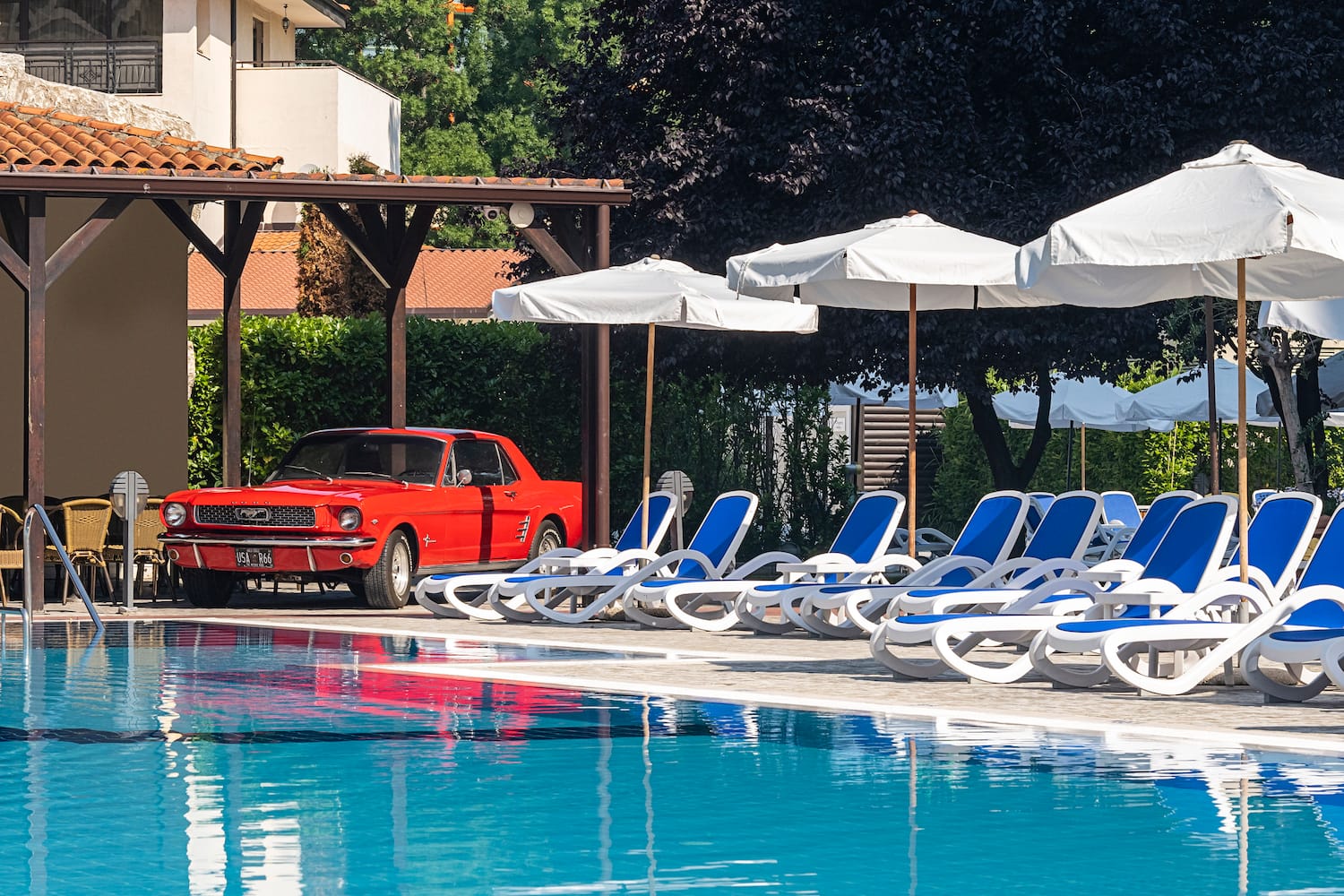 a red car parked next to a pool
