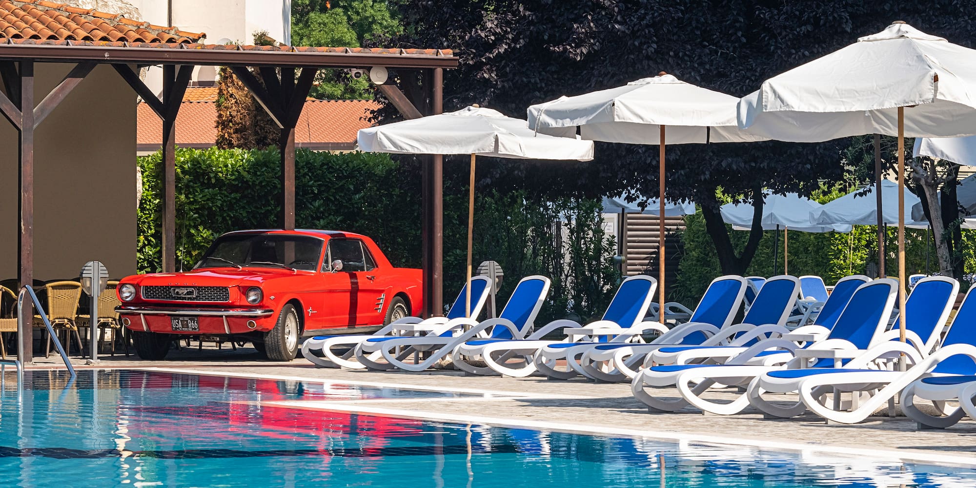 a red car parked next to a pool