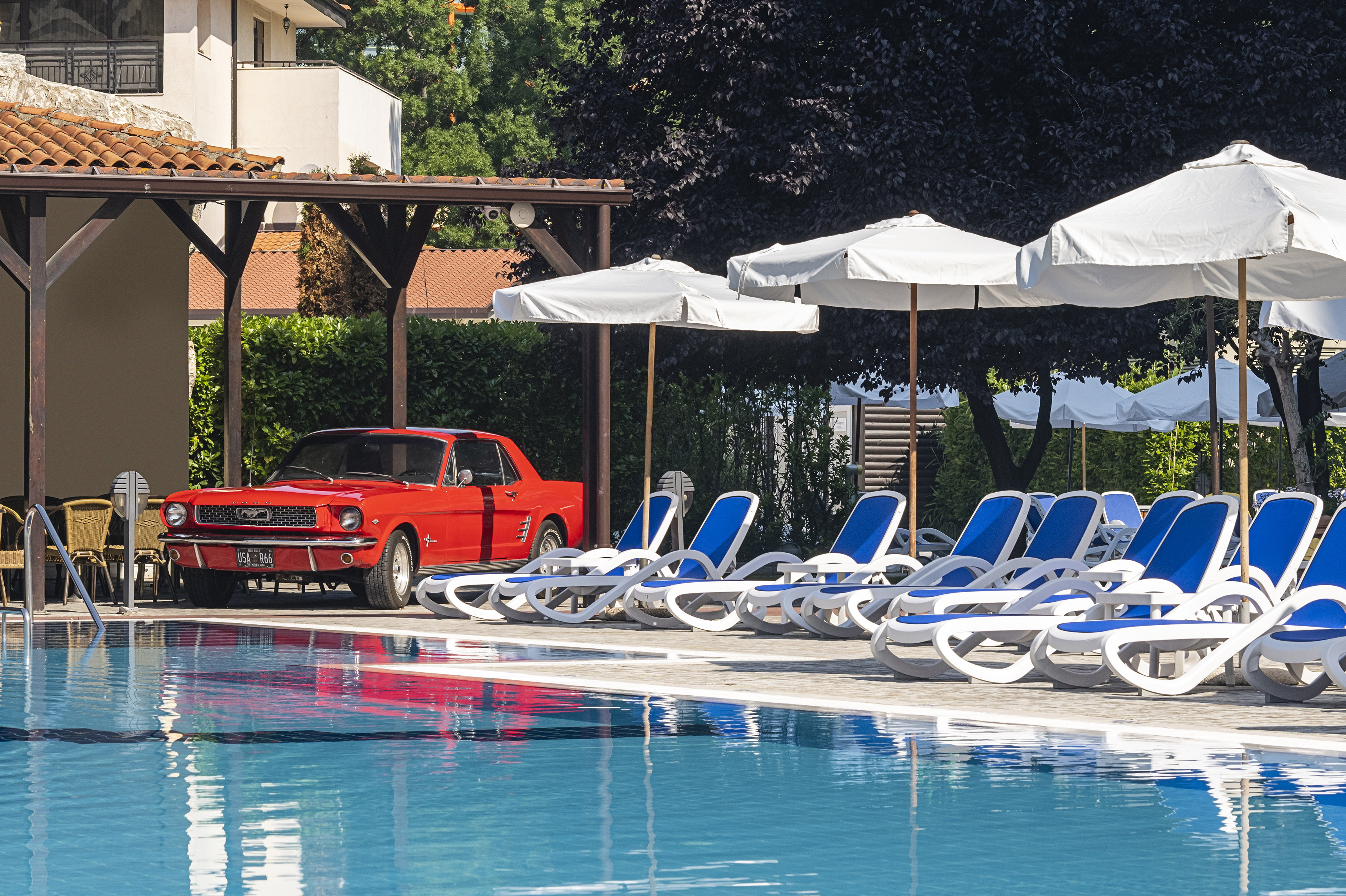 a red car parked next to a pool