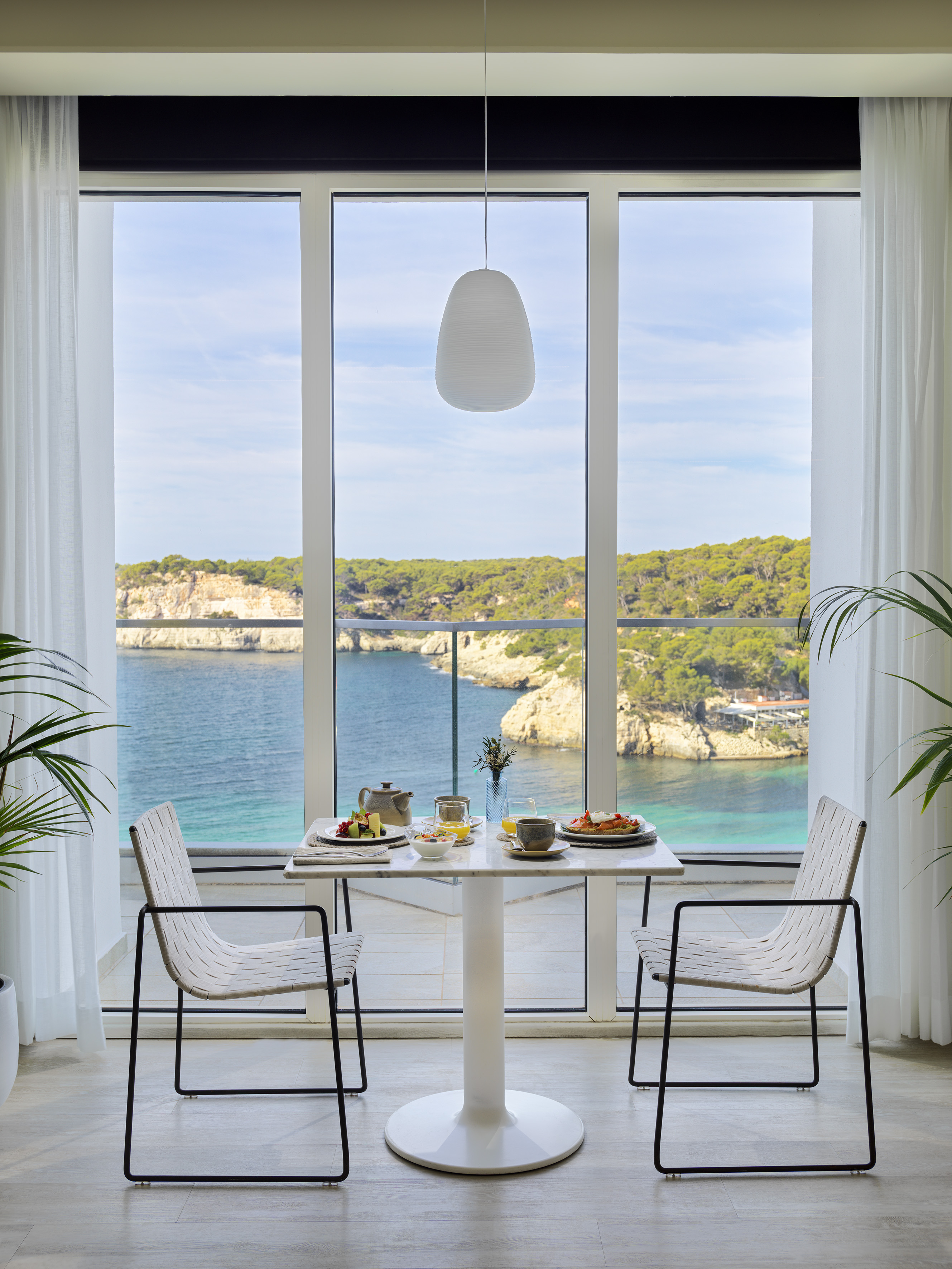 Hotel breakfast with scenic ocean cliff view and modern table setting.