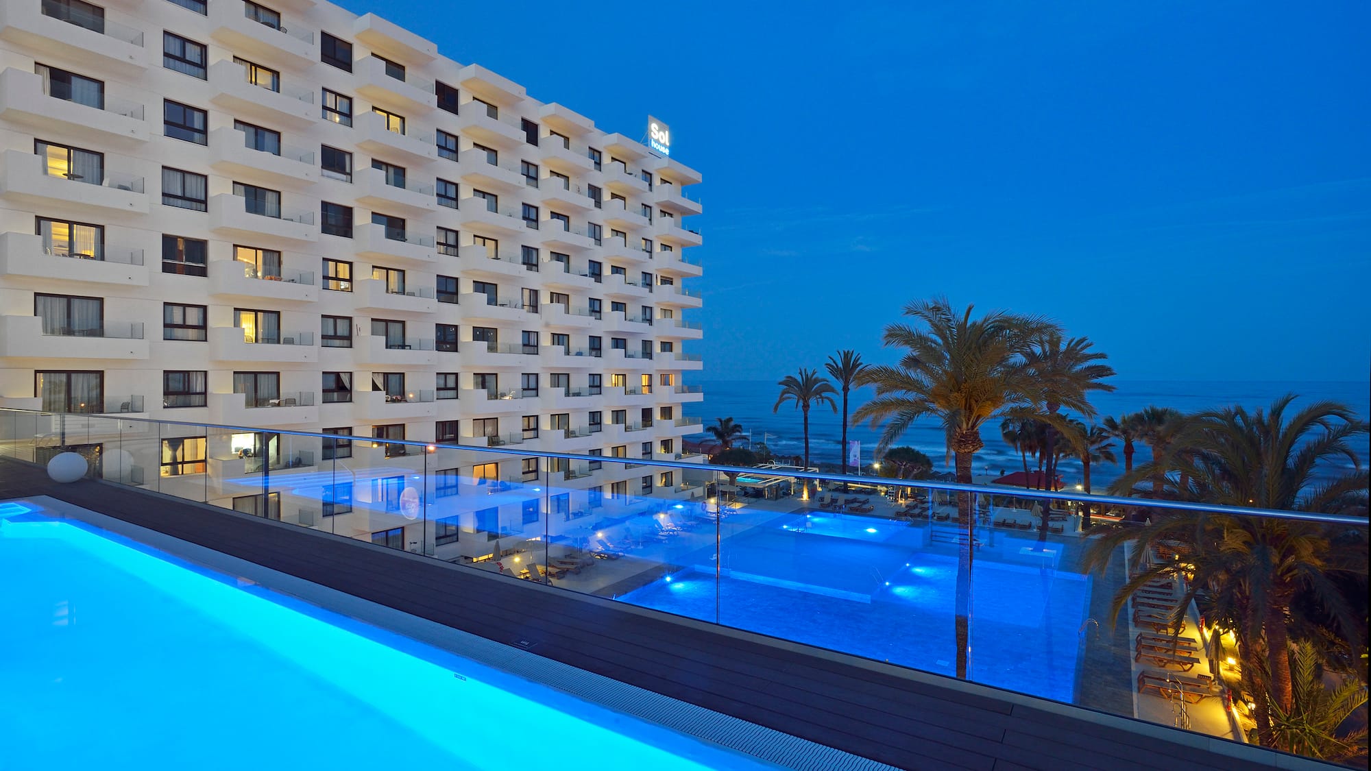 uma piscina com um edifício e palmeiras