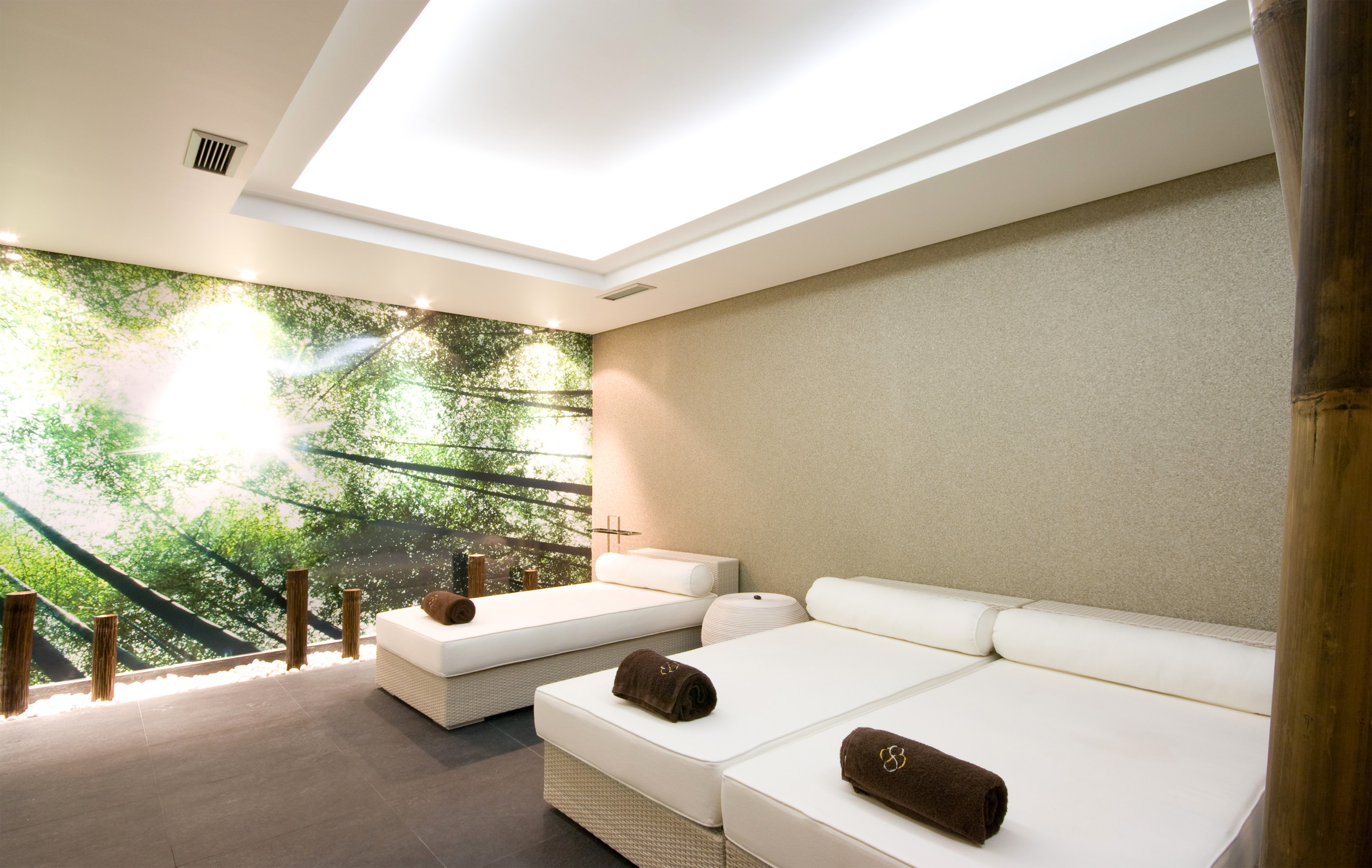 Spa relaxation room with forest mural, white beds, and natural accents.
