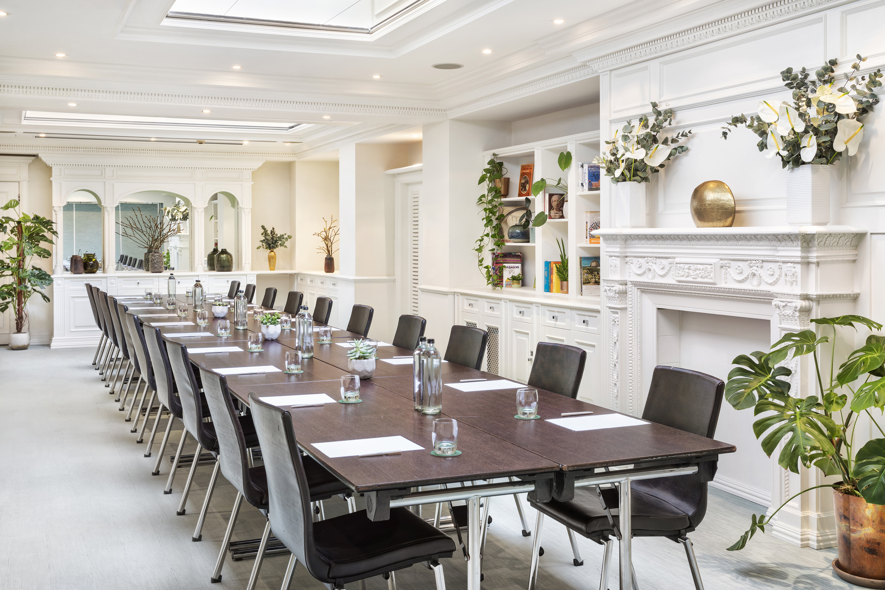 Luxurious boardroom with large conference table, chairs, and white decor.