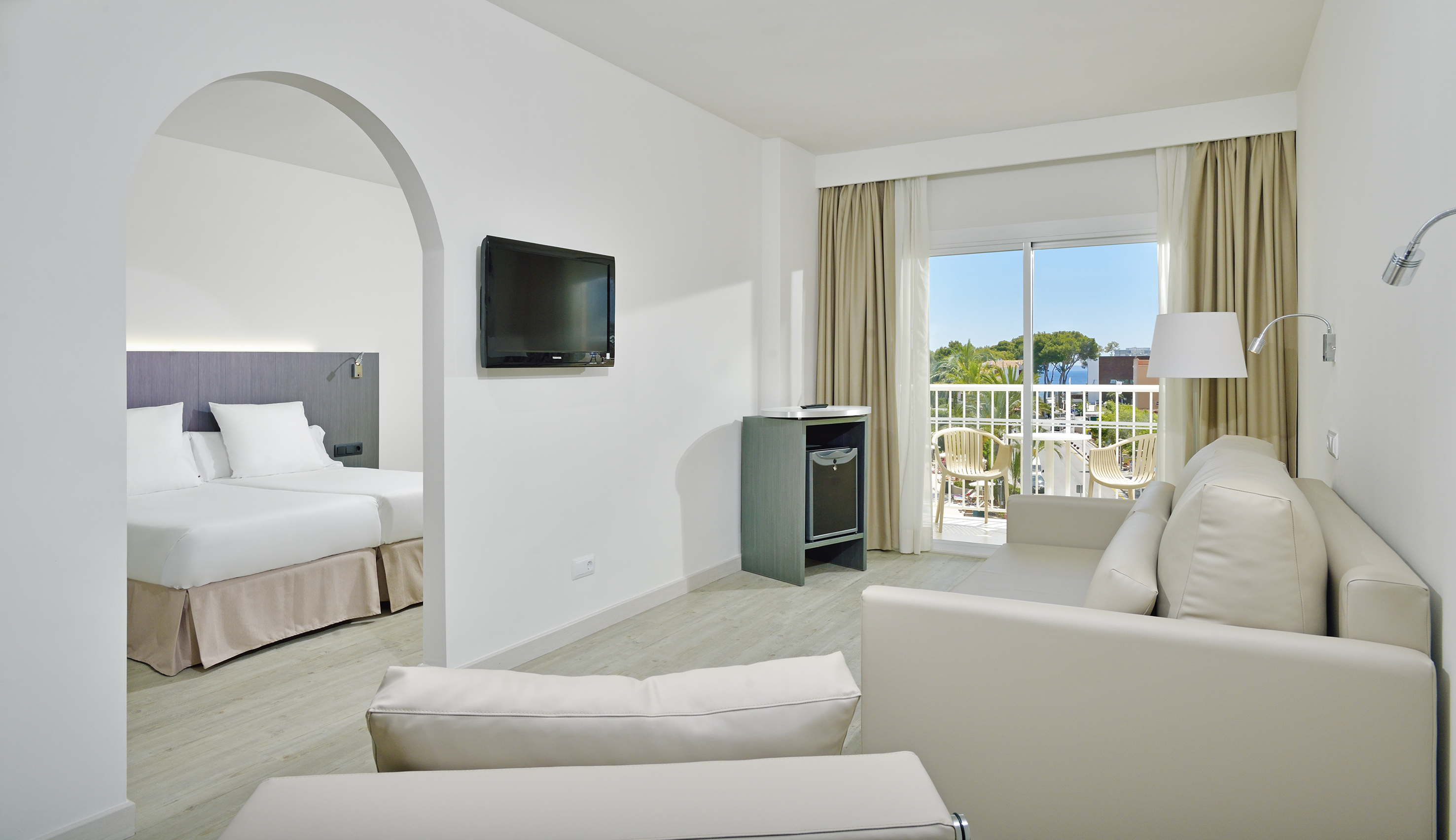 Modern resort suite with living room, bedroom, and balcony with sea view.