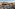 Aerial view of luxurious hotel pool, manicured gardens, and city buildings.