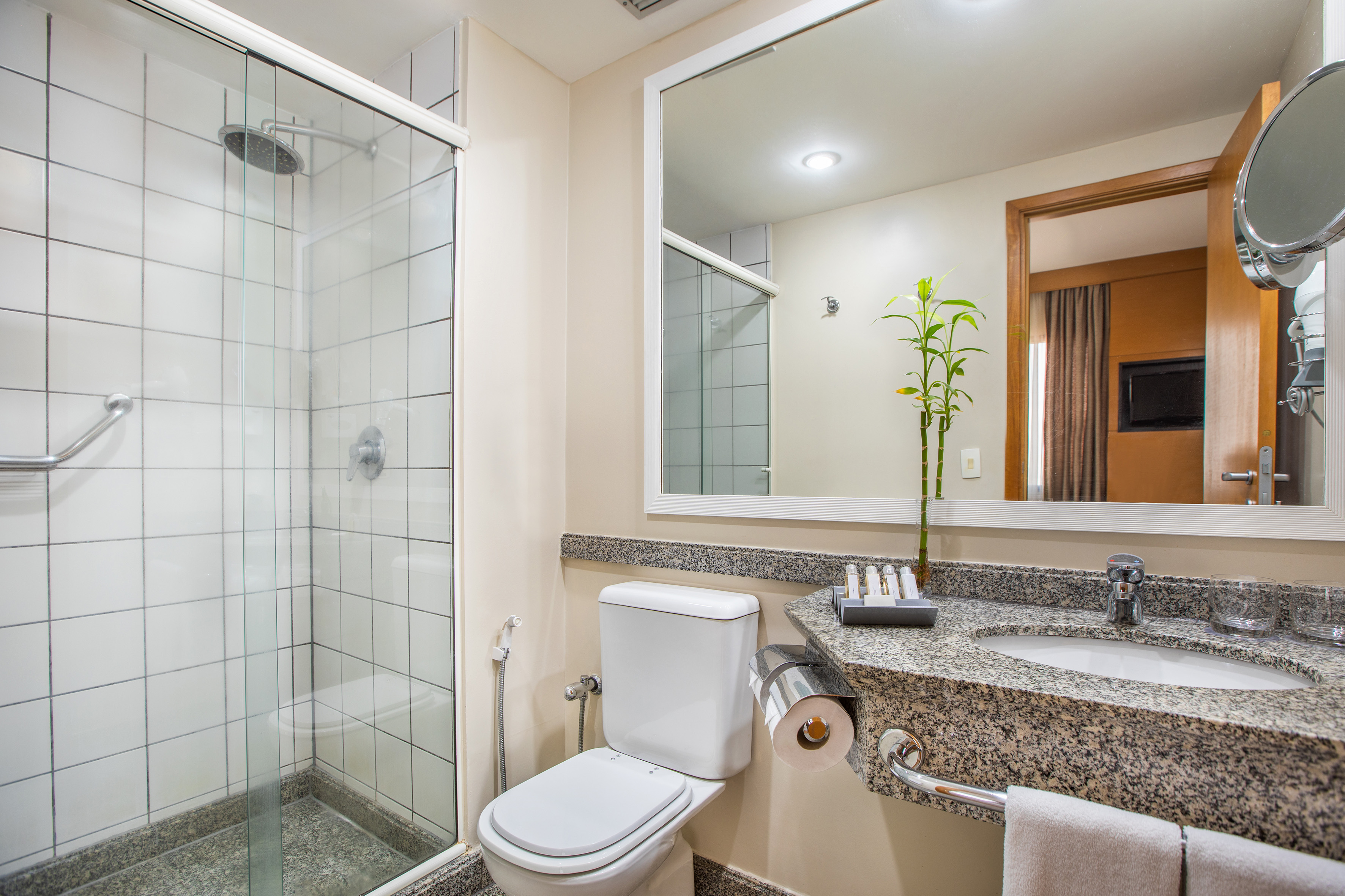 Clean hotel bathroom with walk-in shower, toilet, granite vanity, and mirror.