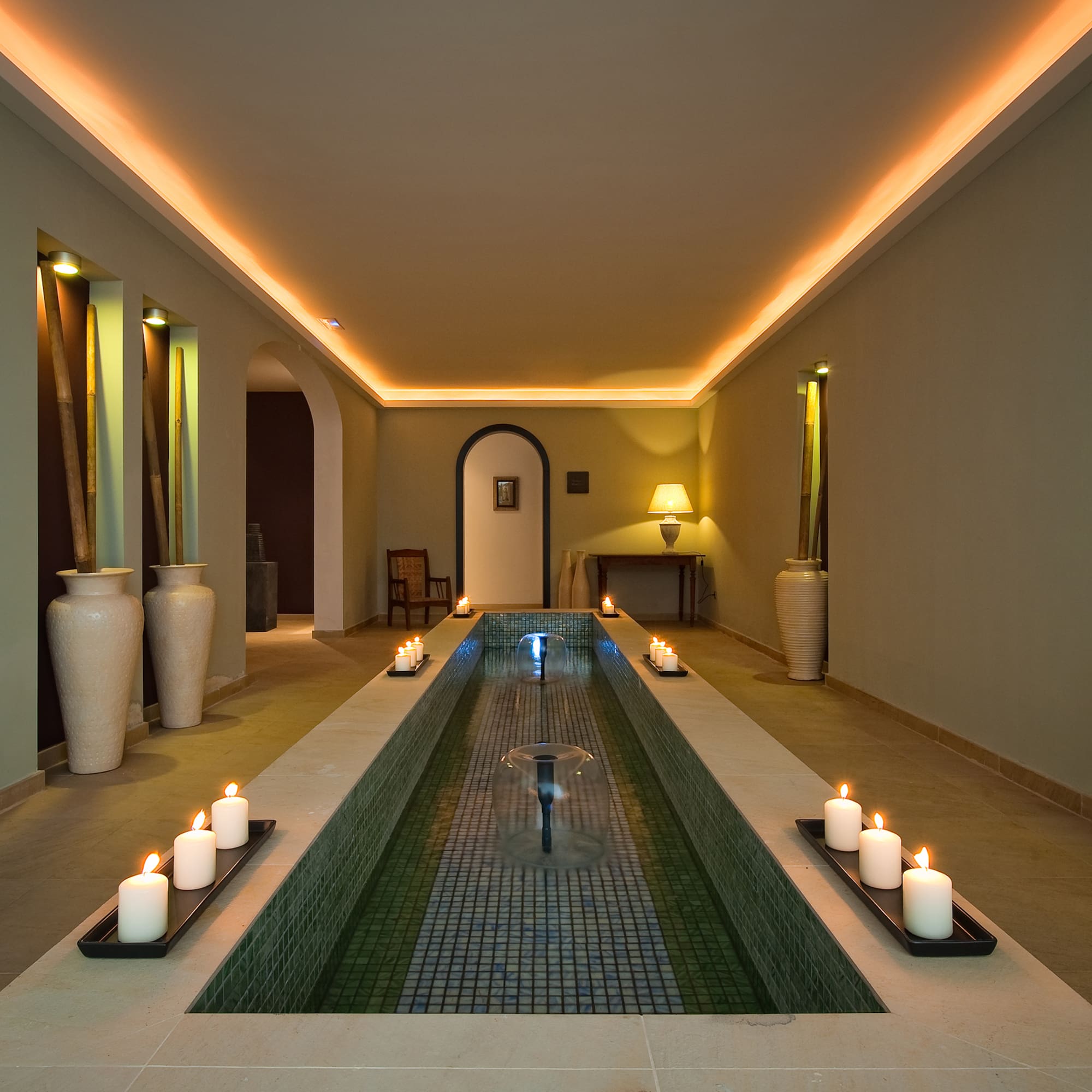a long rectangular pool with candles in the middle