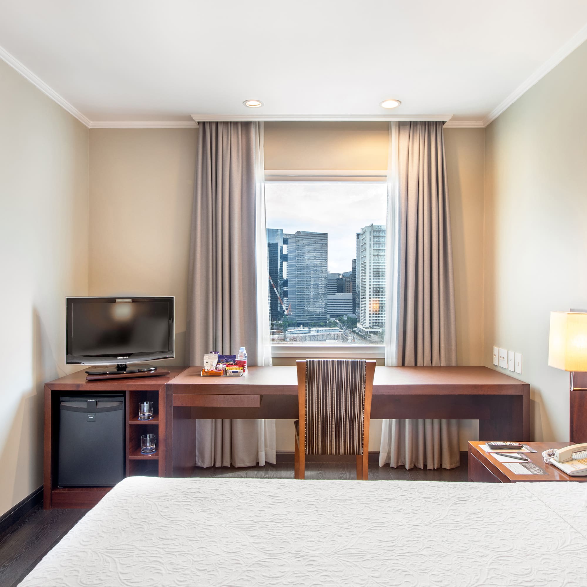 a room with a bed and a desk and a television