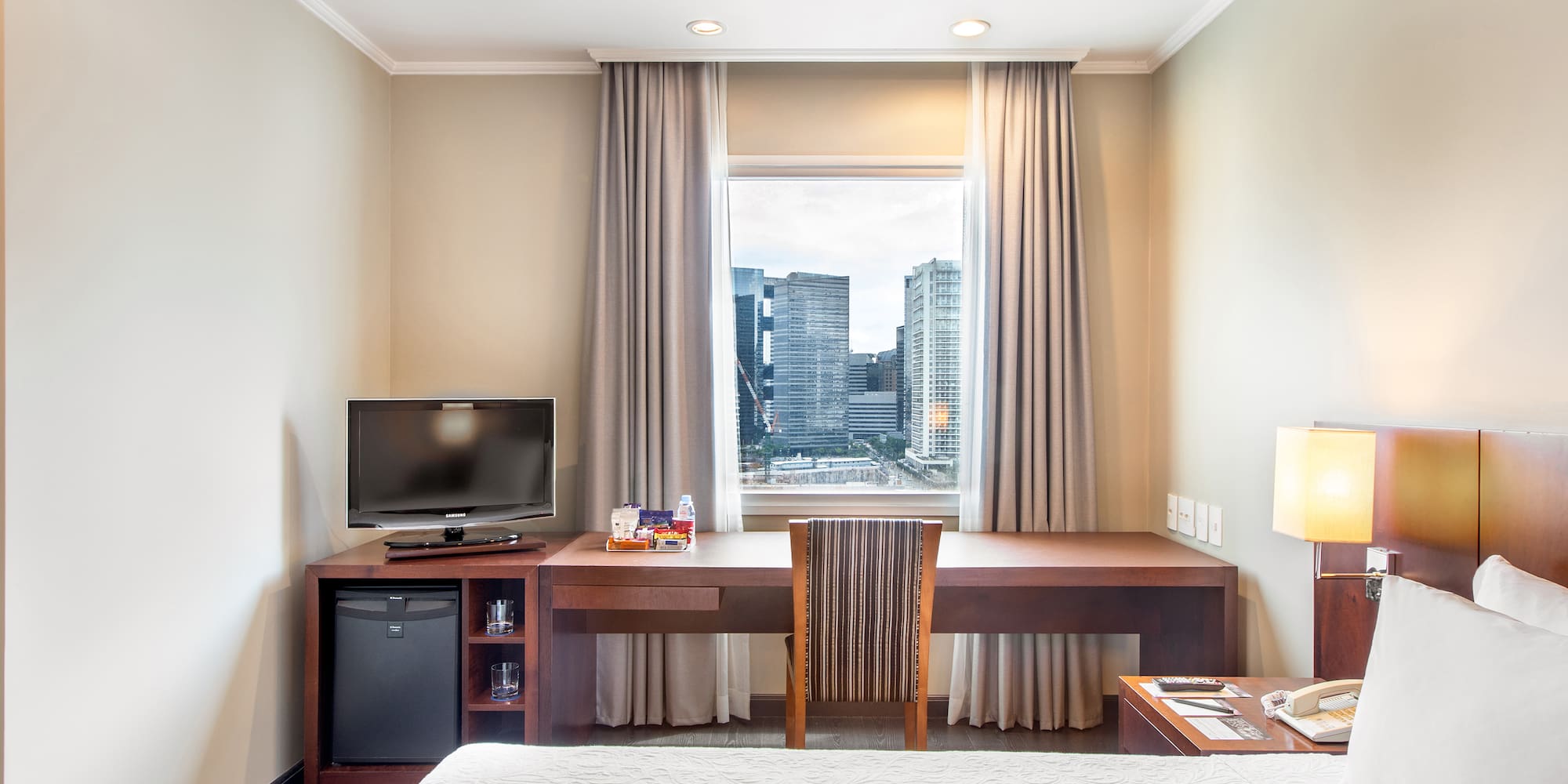 a room with a bed and a desk and a television