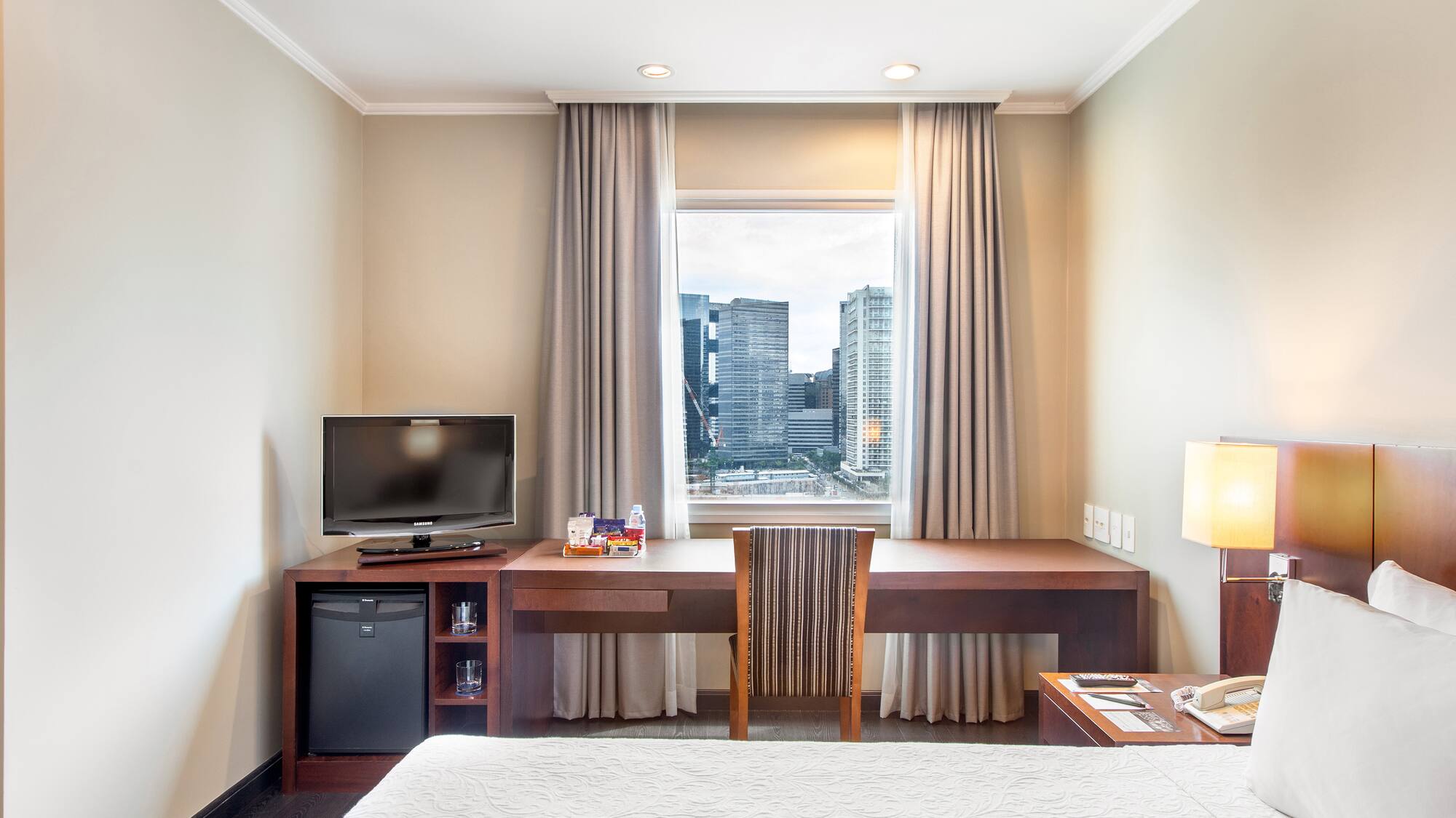 a room with a bed and a desk and a television