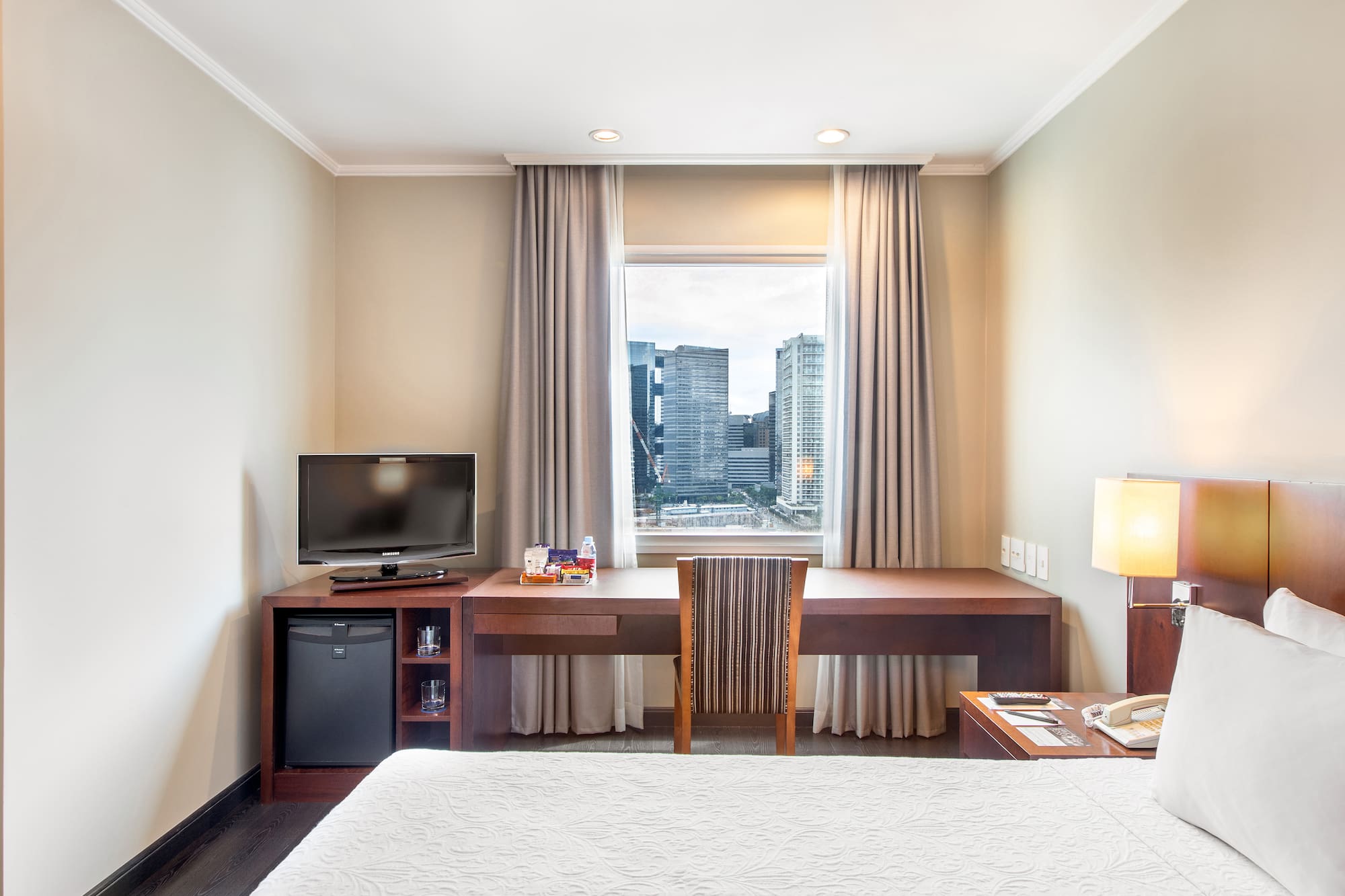 a room with a bed and a desk and a television