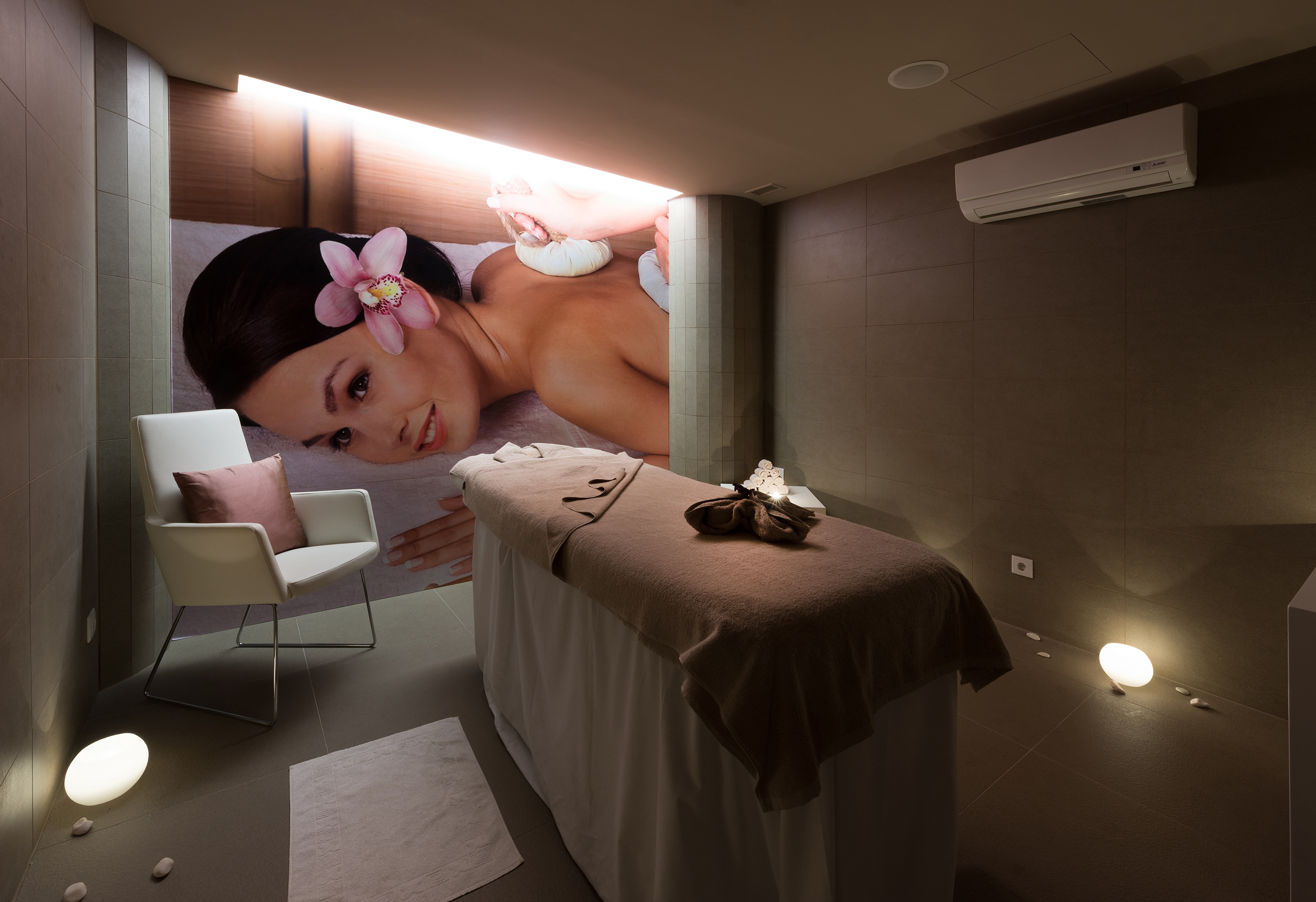 Relaxing spa treatment room with wall mural, massage bed, and ambient lighting.