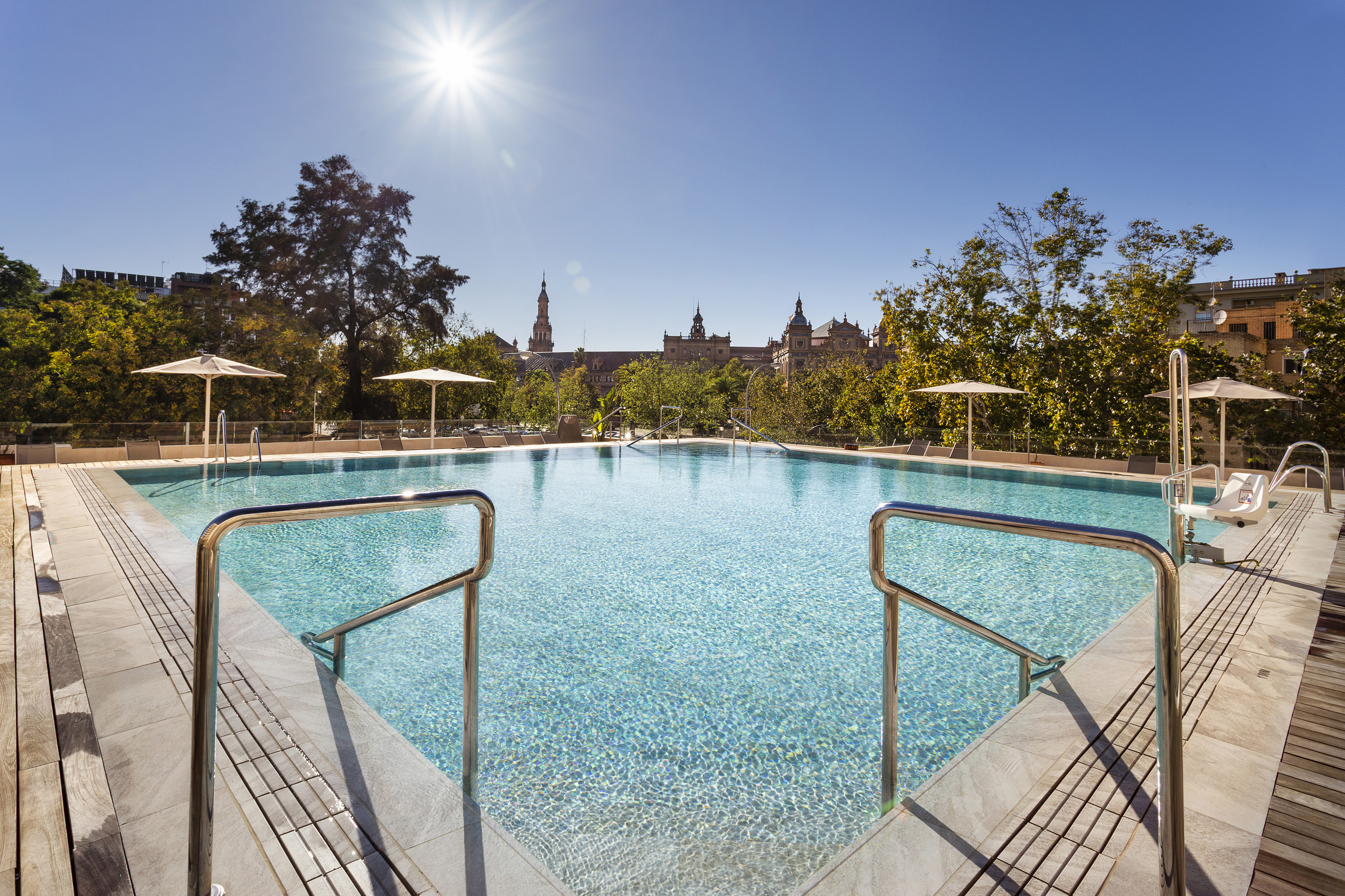 Sunny hotel swimming pool overlooking Seville city skyline.