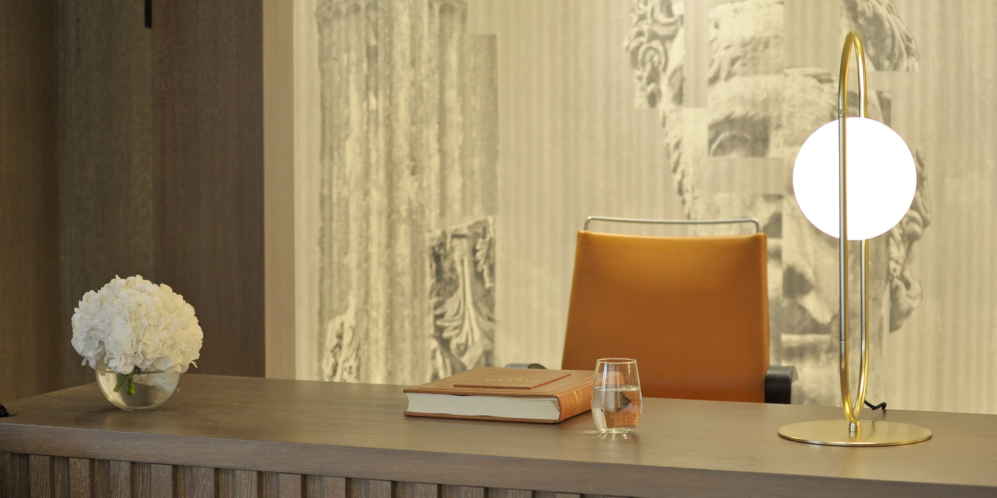 a desk with a book and a vase of flowers on it