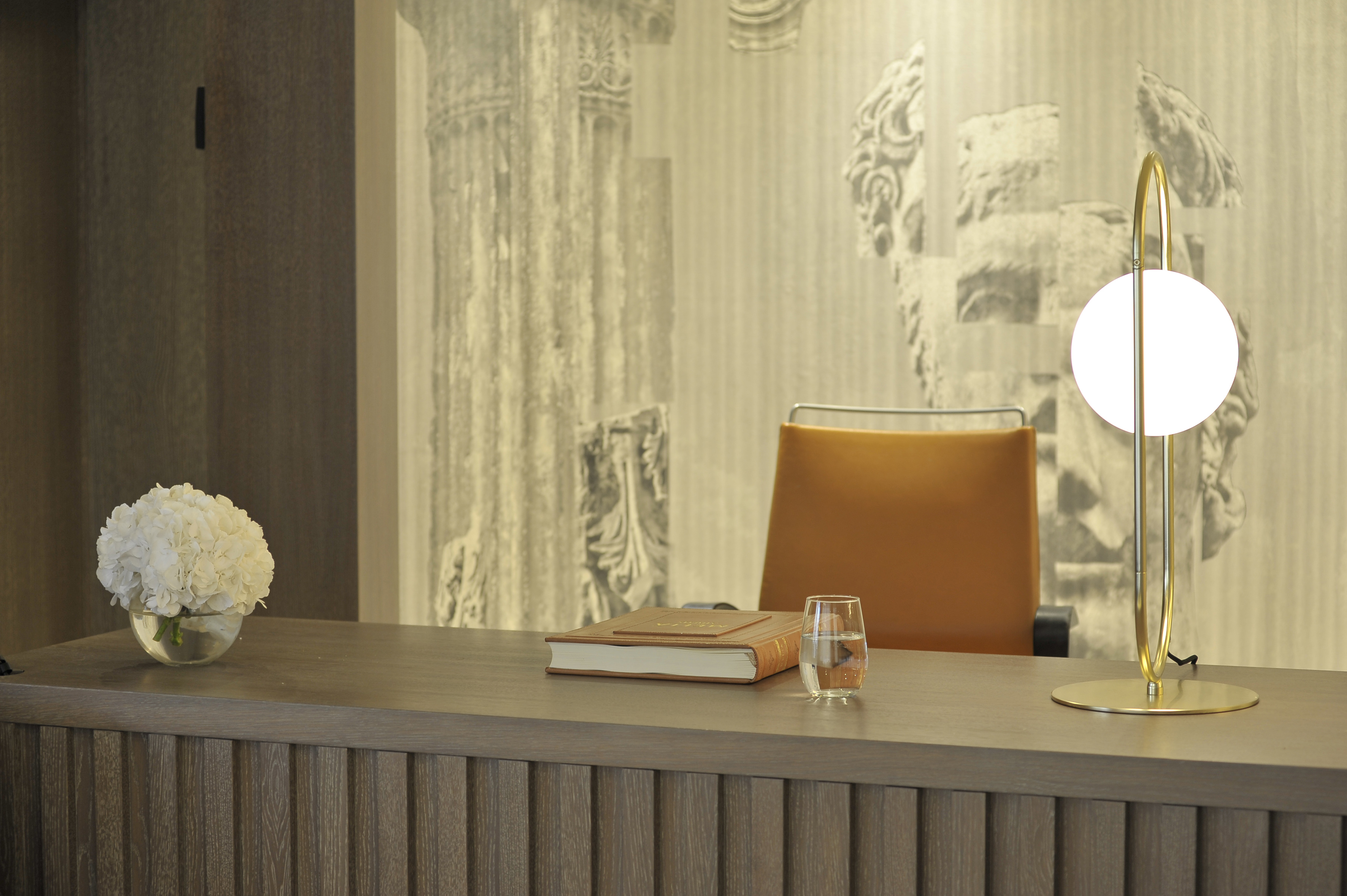 a desk with a book and a vase of flowers on it