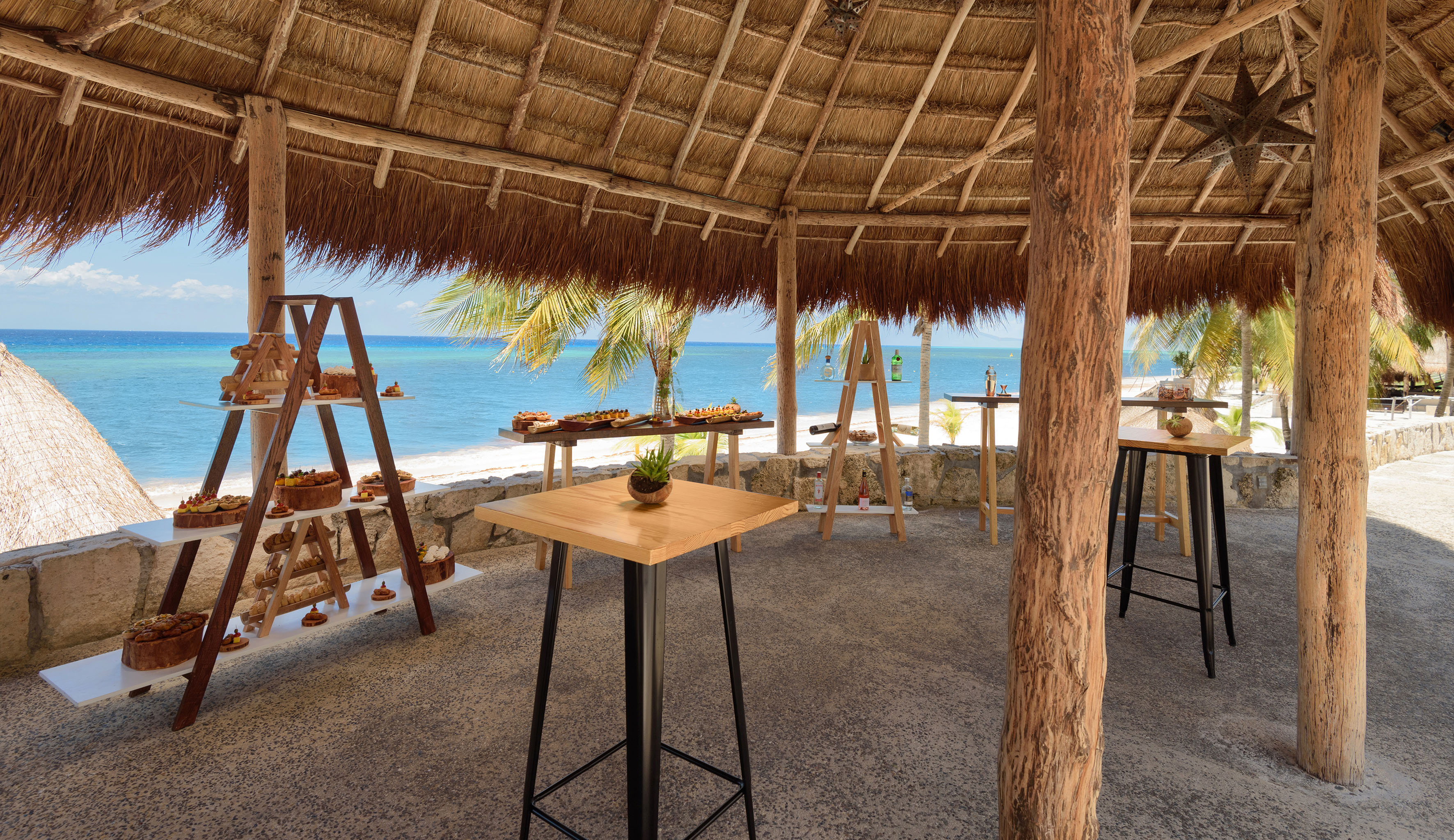 Tropical palapa beachfront catering with appetizers and ocean view.